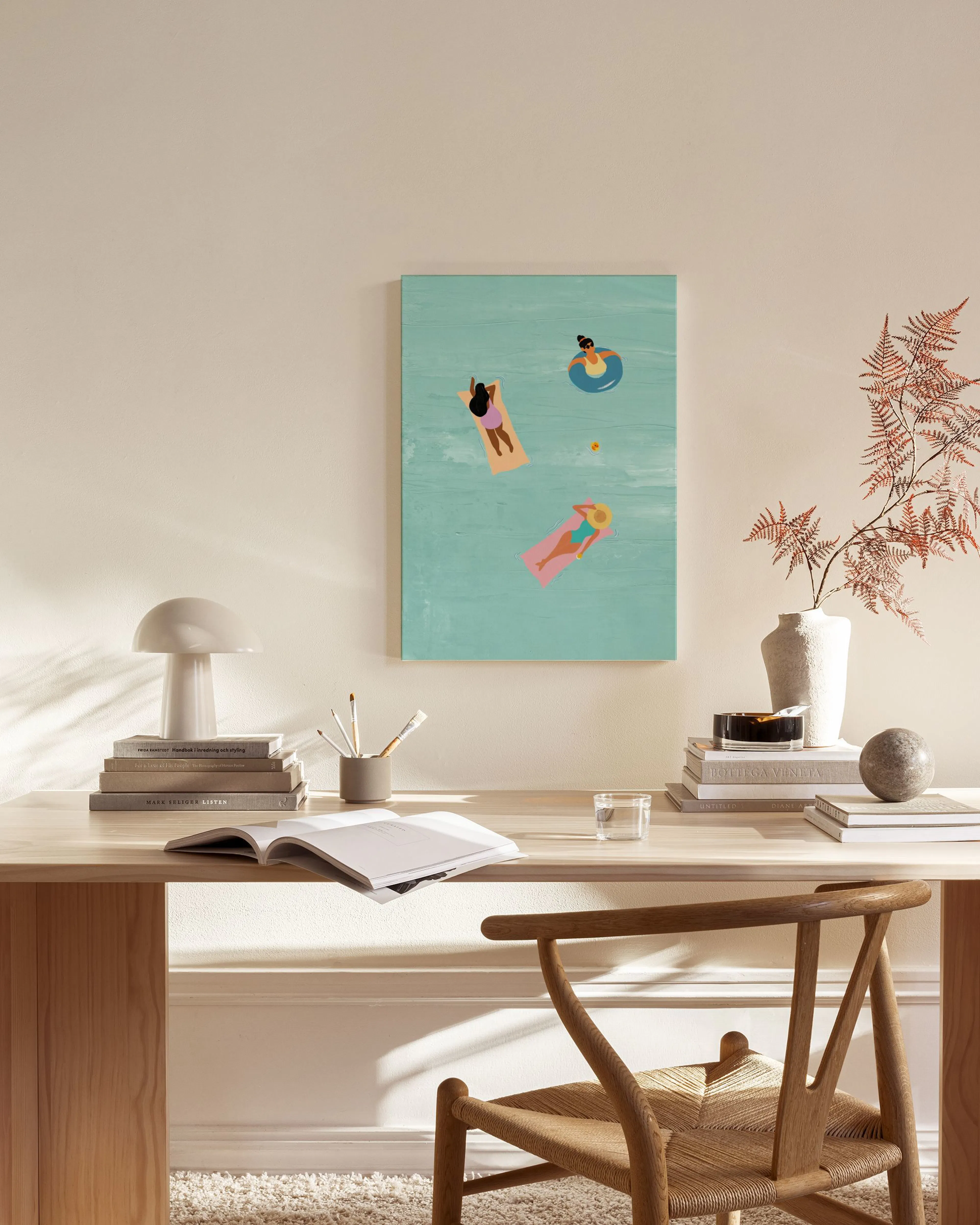 A canvas print depicting three people relaxing on floats in a blue pool, displayed above a wooden bench in a minimalist living r