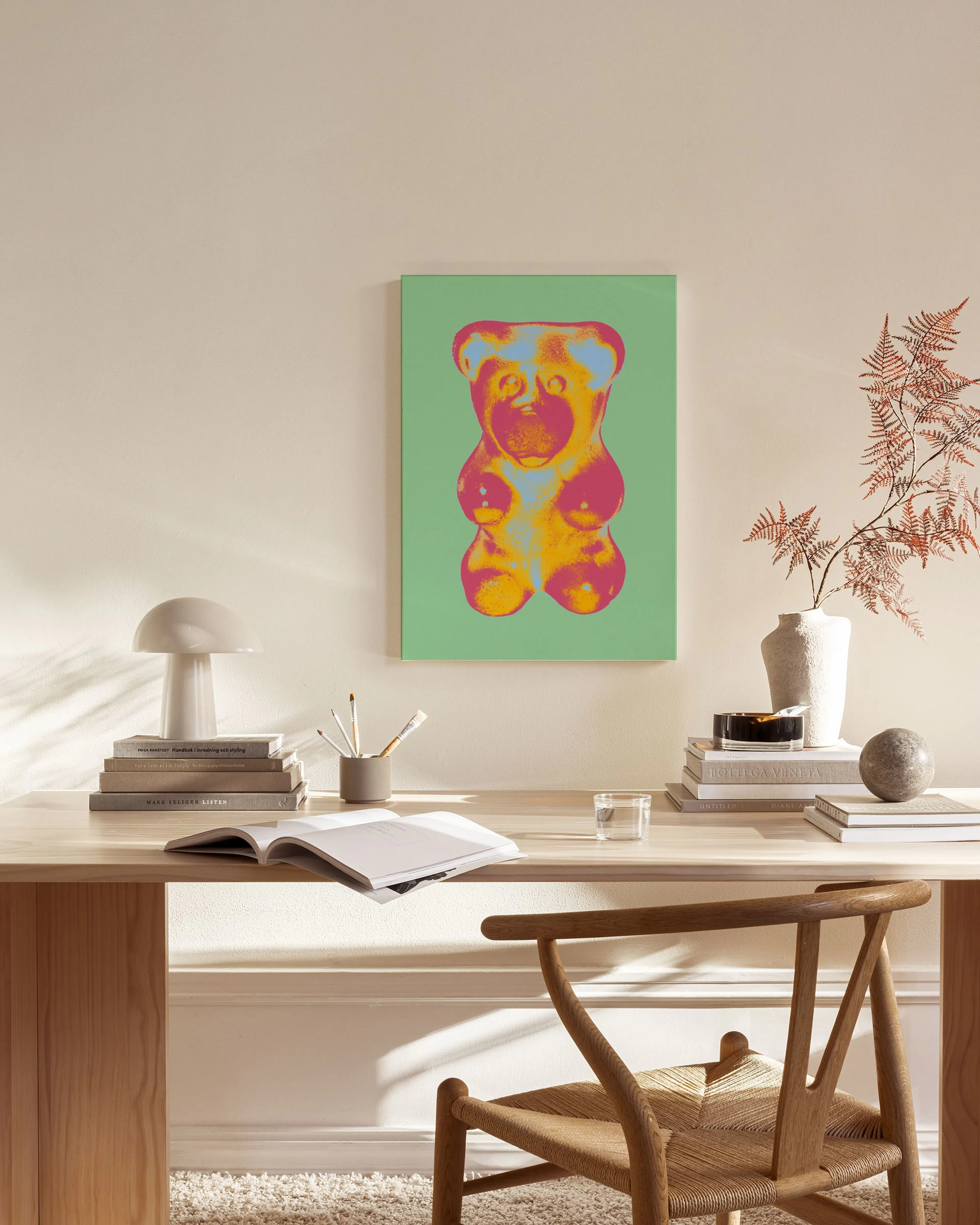 Pop art style gummy bear in pink, orange, and blue on a green background, hanging in a modern living room.