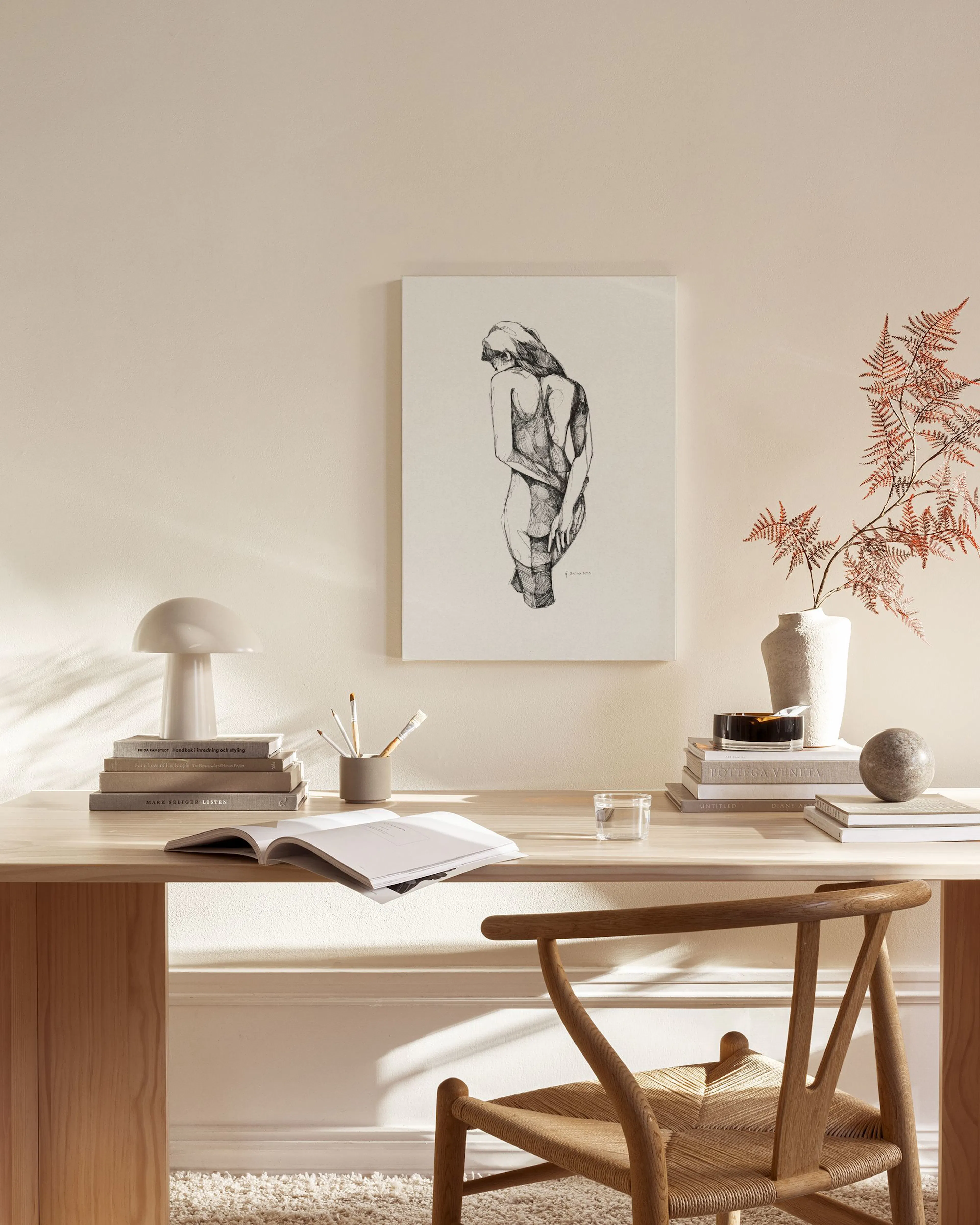 Une toile représentant un nu féminin de dos, aux traits de crayon noir, accrochée dans un salon lumineux au-dessus dun banc en b
