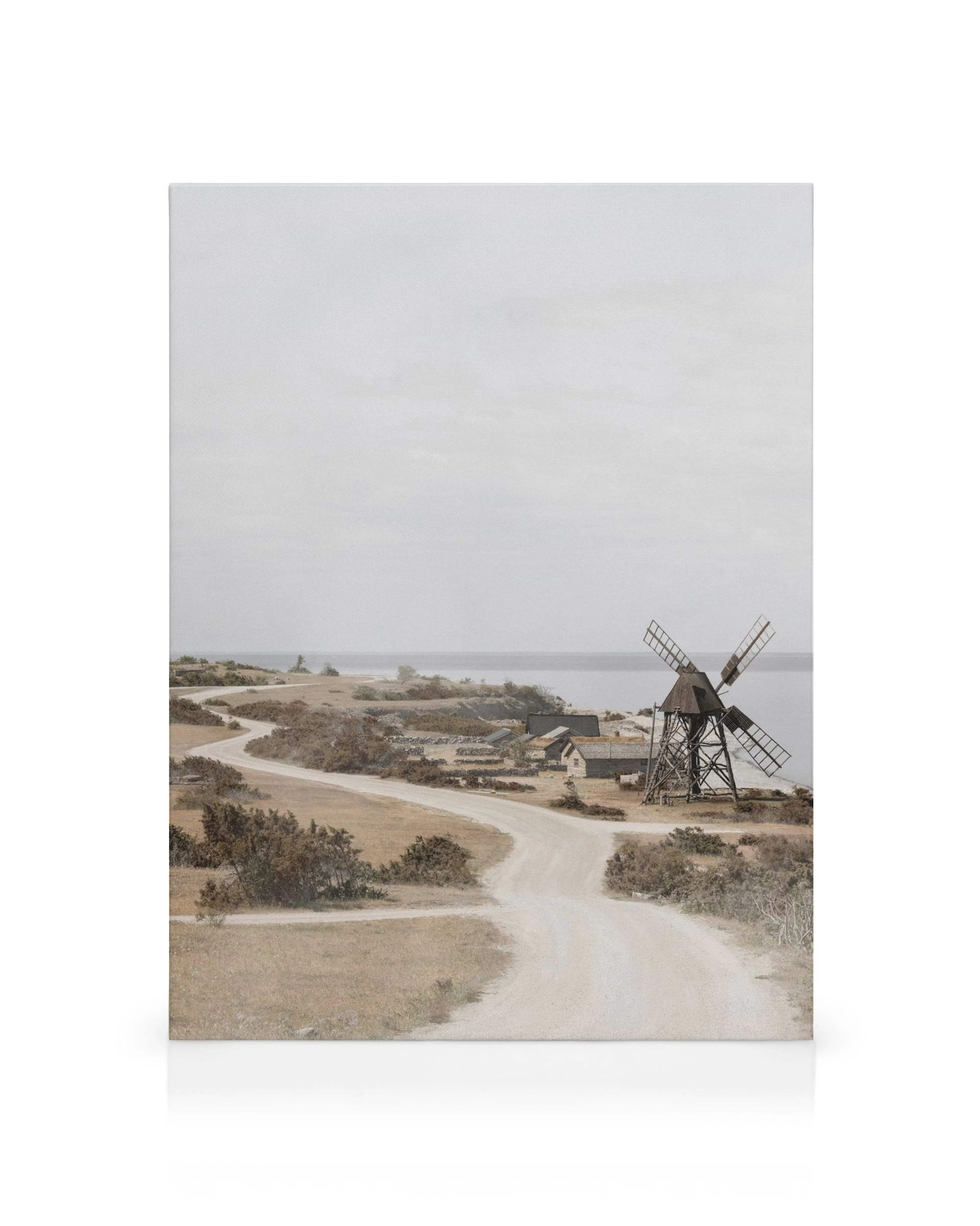 Toile de paysage aride avec route sinueuse, moulin à vent, arbustes et mer sous ciel nuageux