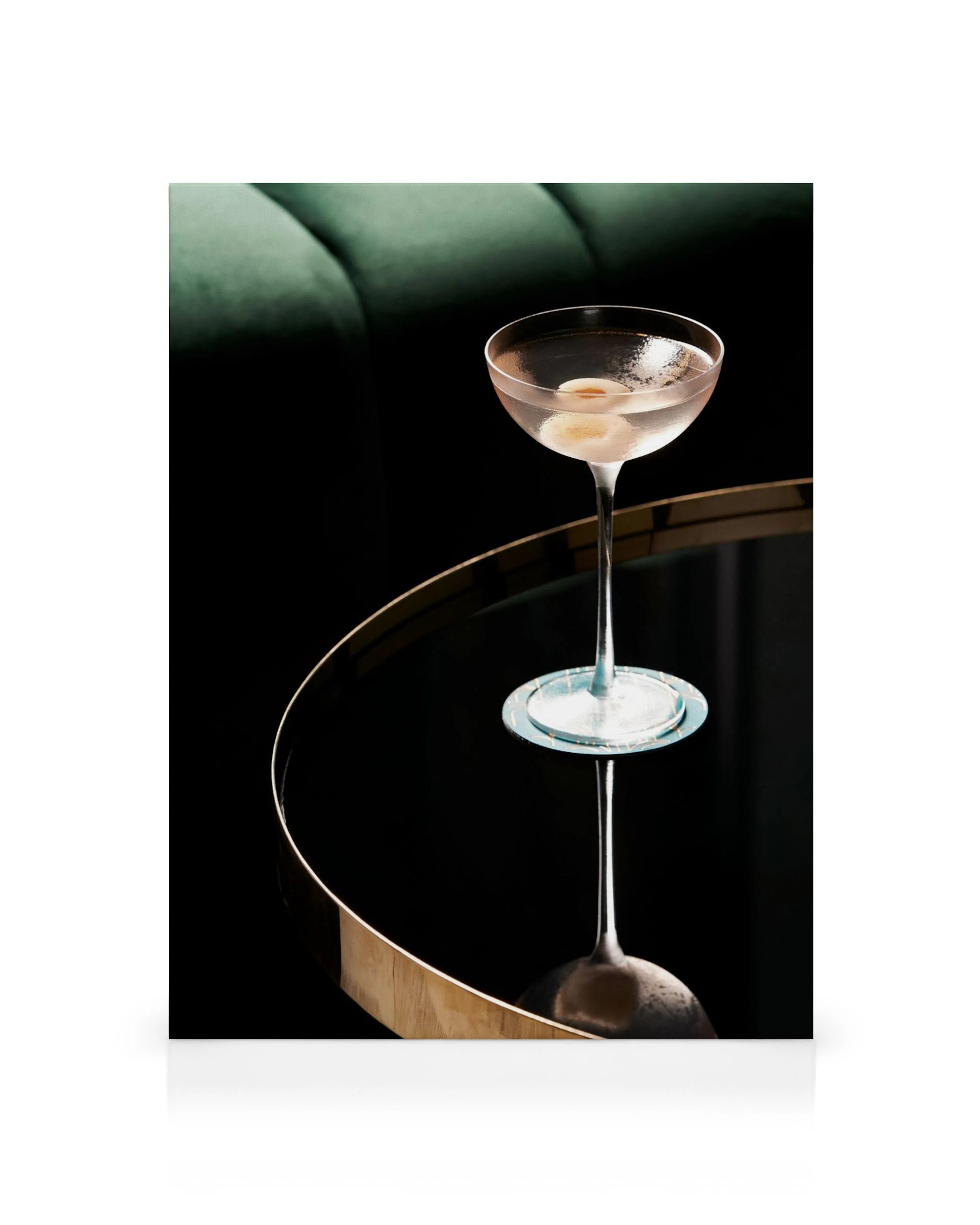 Cocktail glass on a mirrored table with a dark background and green cushion for canvas print