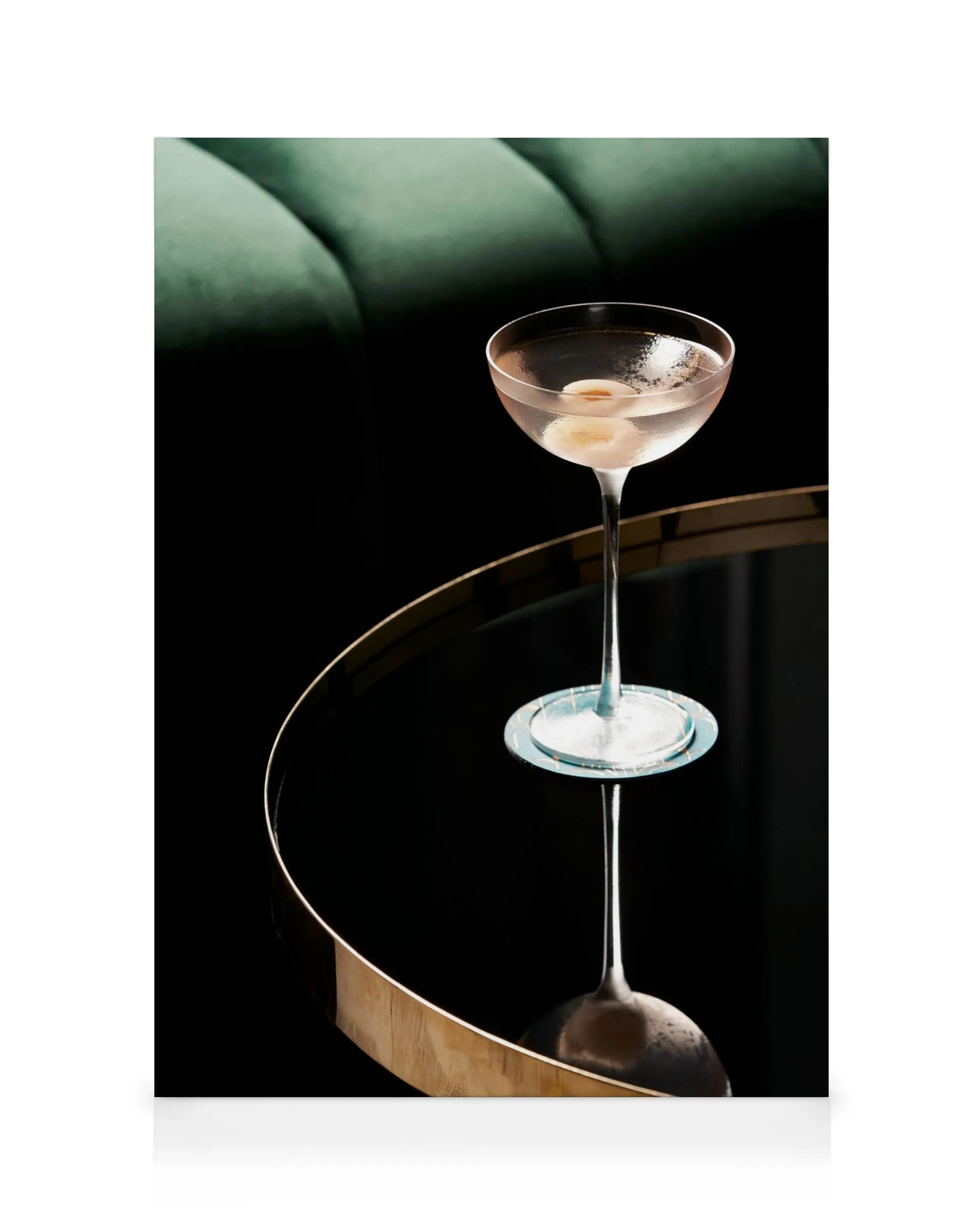 Canvas met cocktailglas en olijven op spiegelende tafel, met groene gewatteerde achtergrond. Drinktijd decoratie.