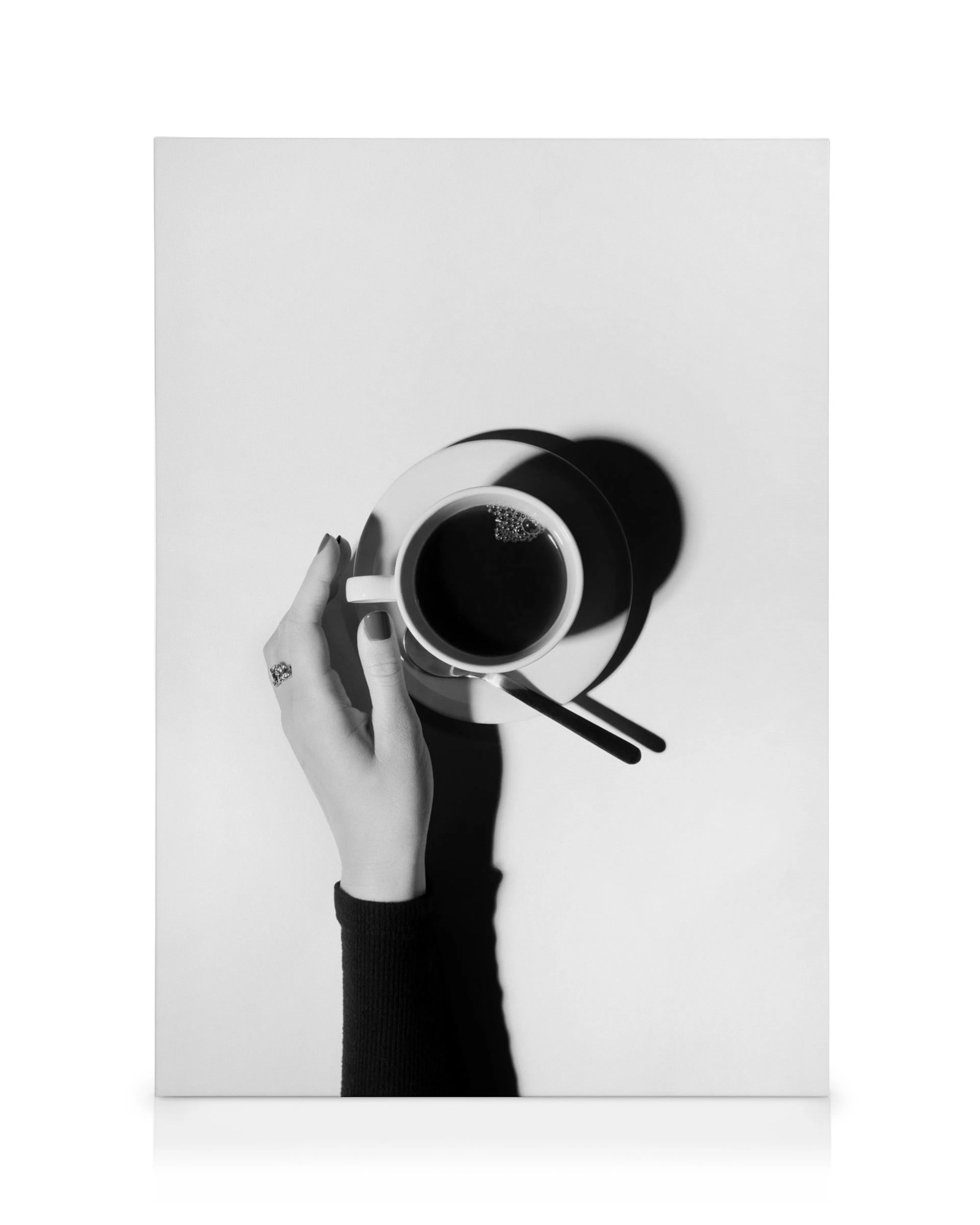 Black and white coffee canvas print with hand holding a cup, saucer, and spoon, perfect for dining room or kitchen art.