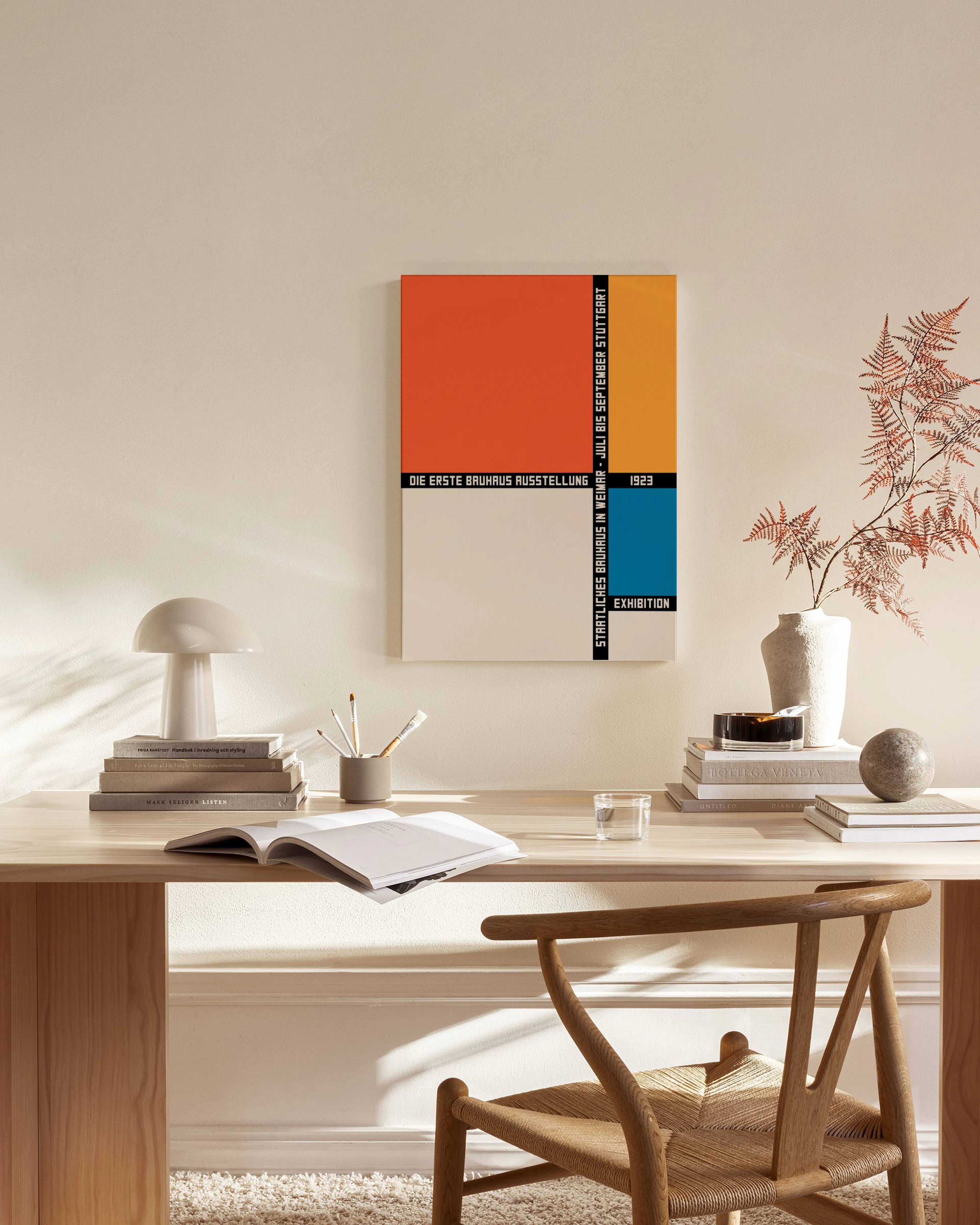 Ein Bauhaus-Leinwandbild mit orangen, beigen und blauen Rechtecken hängt über einem Sideboard in einem modernen Wohnzimmer.