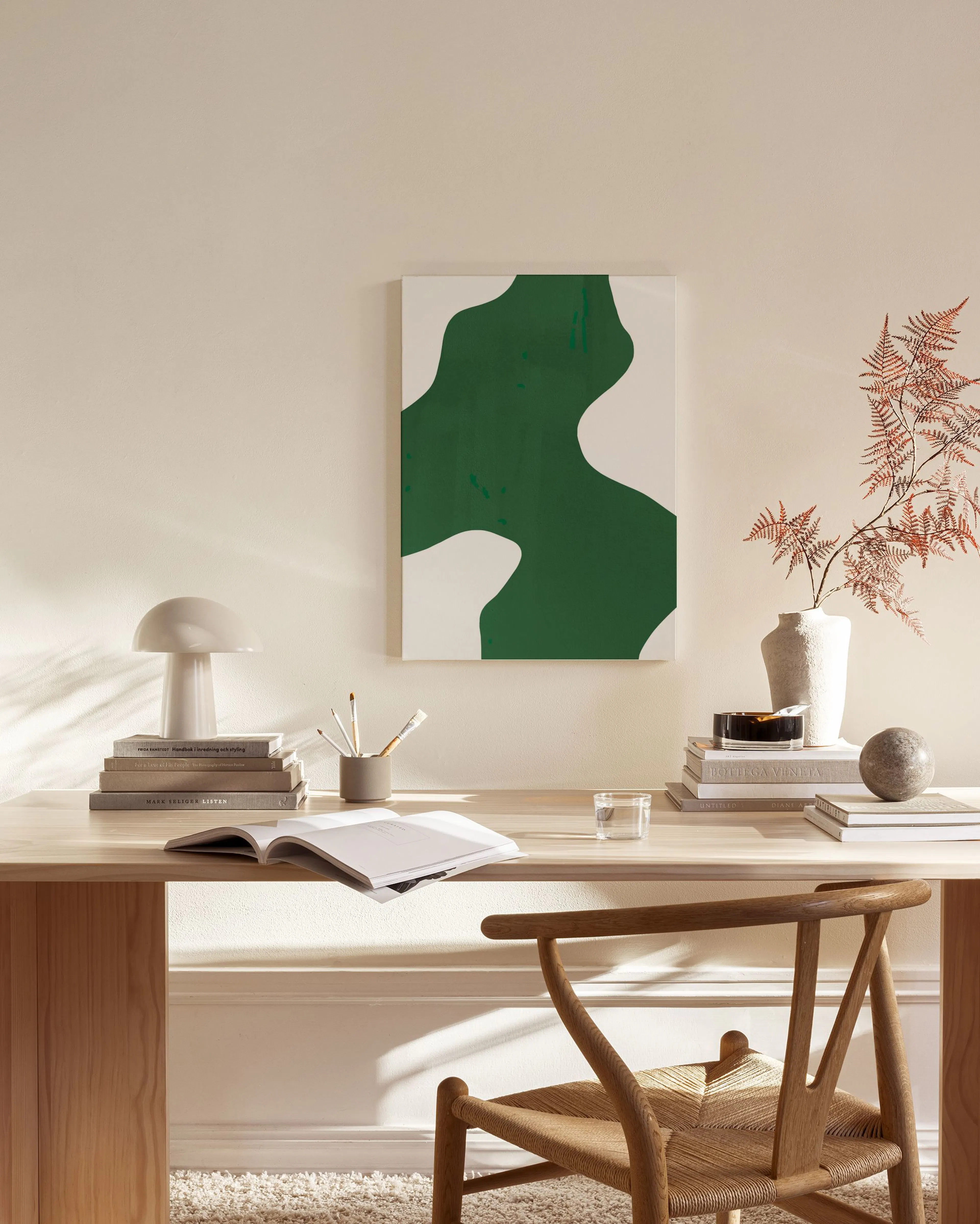 Lienzo abstracto con formas orgánicas verdes sobre fondo blanco, colgado en una sala de estar moderna.