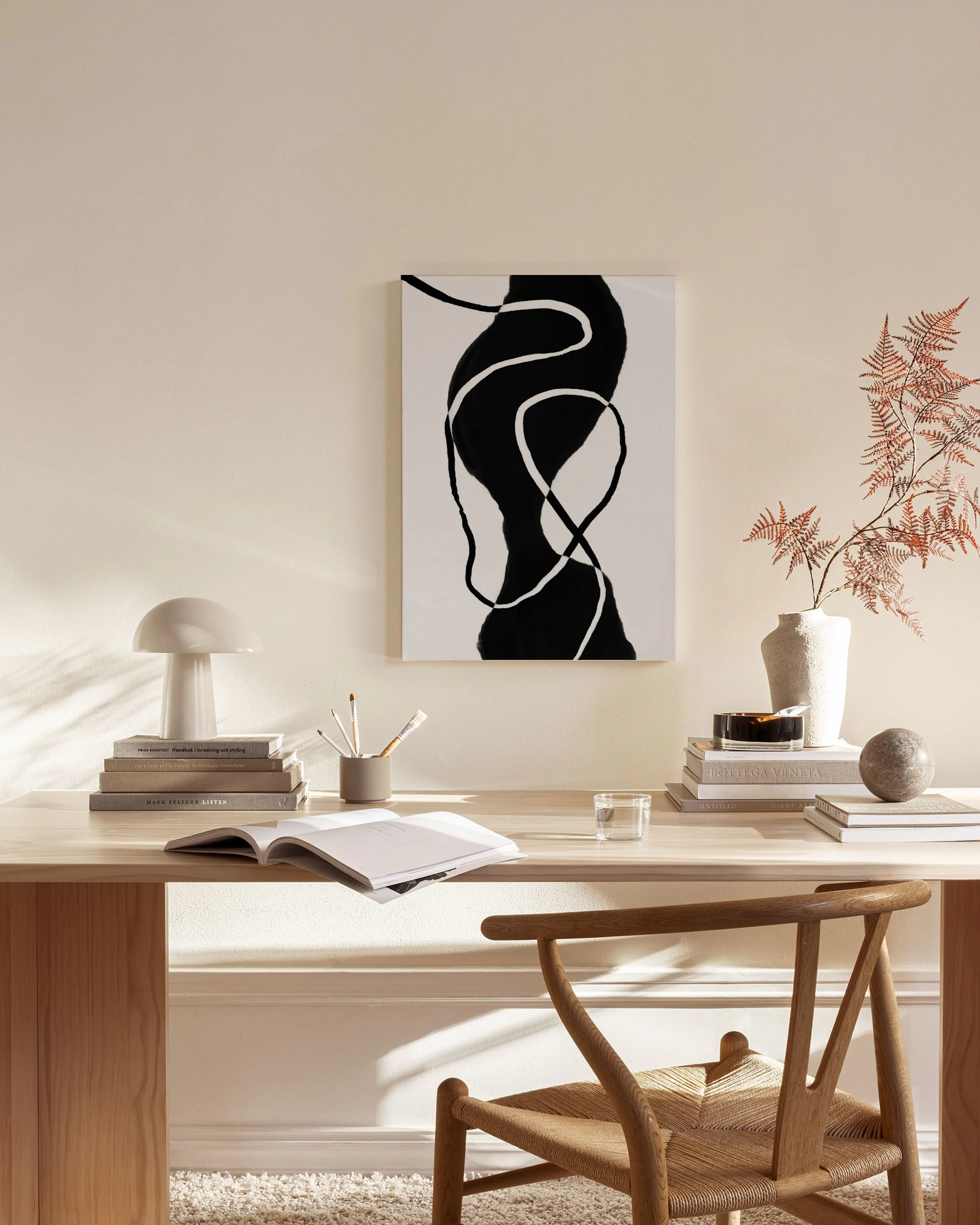 Leinwandbild mit schwarzen organischen Formen und weißen Linien, über einem Sideboard in einem Wohnzimmer.