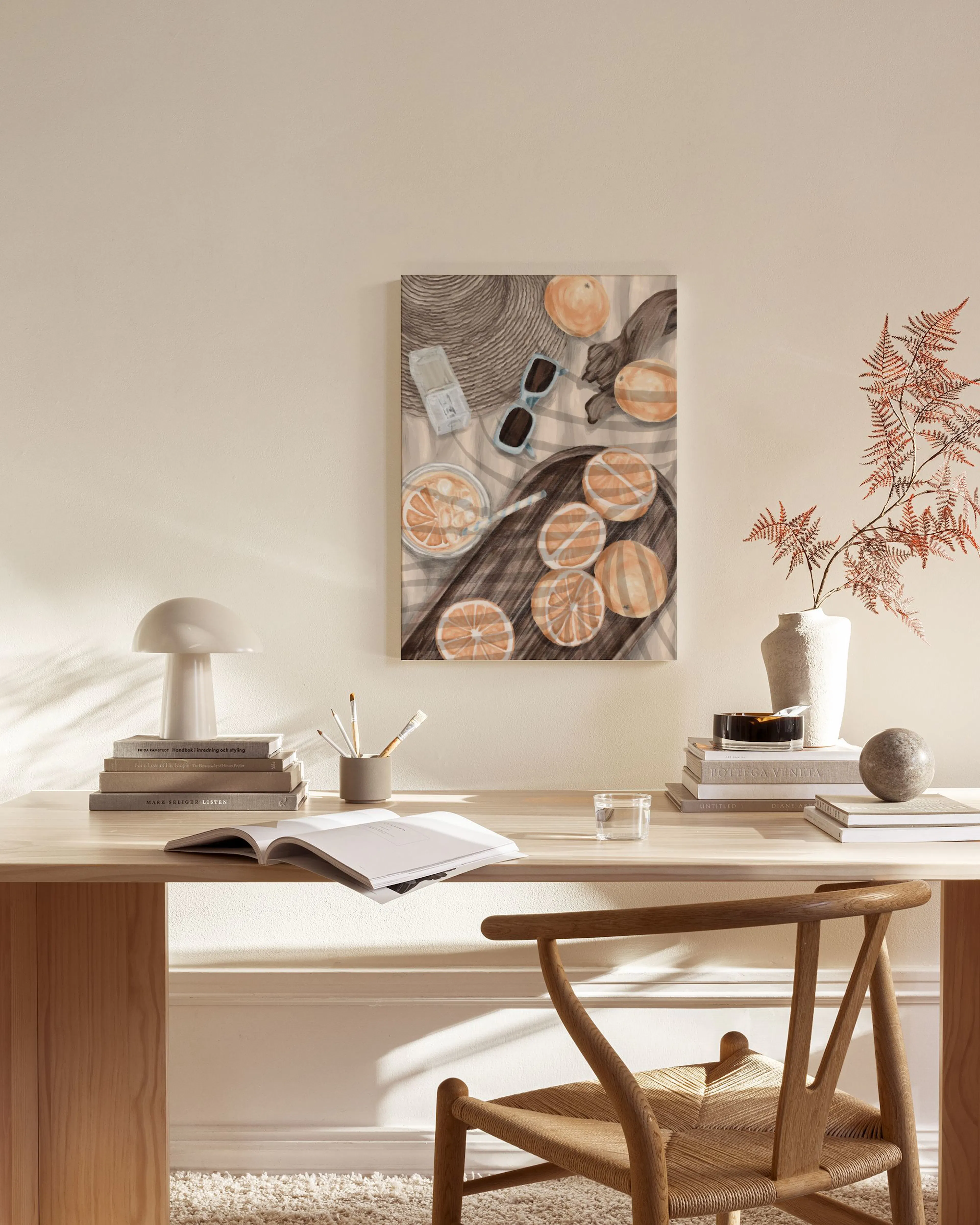 Toile illustrée dune nature morte estivale avec chapeau, lunettes et agrumes, accrochée dans un salon moderne.