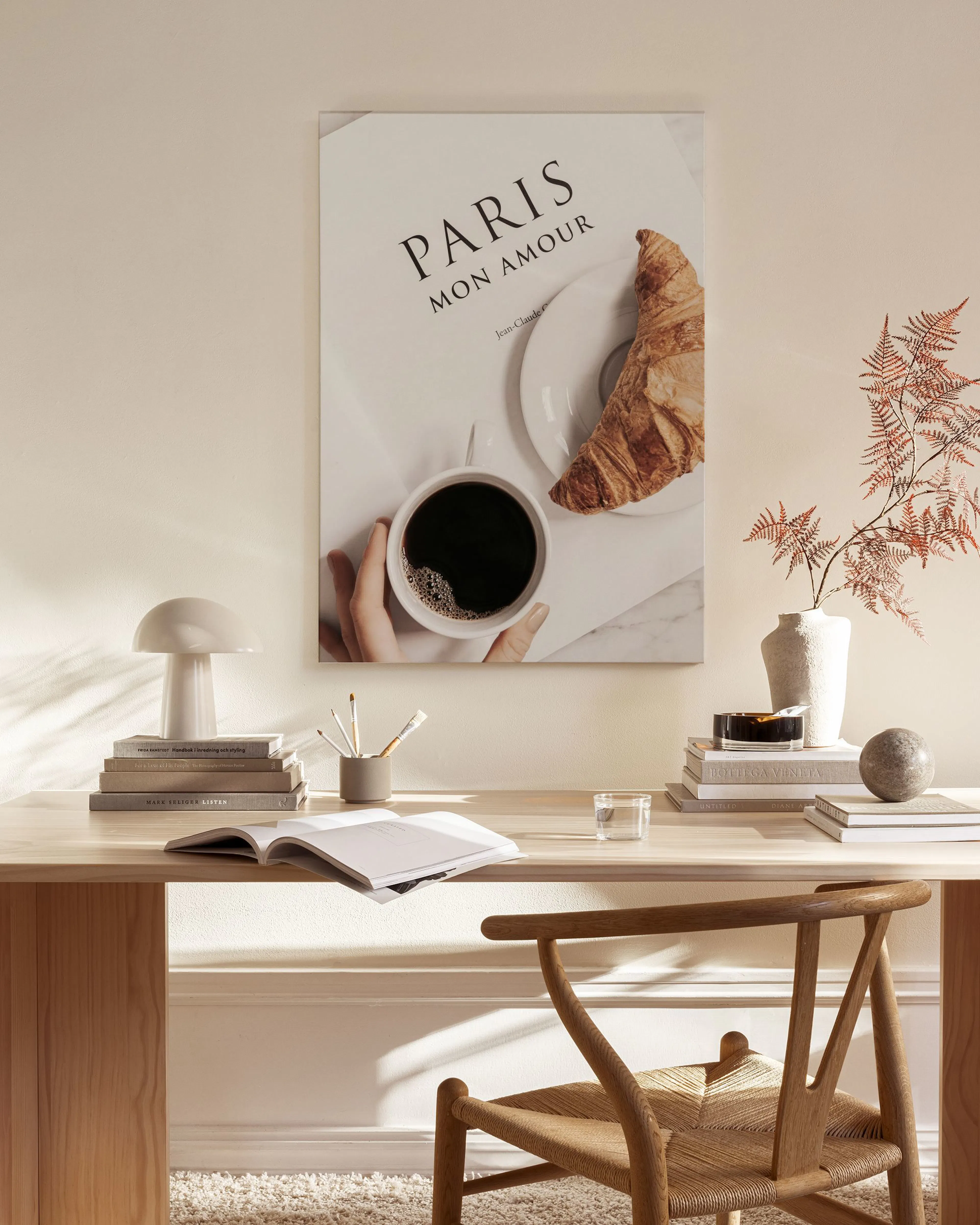 Obraz na plátne s nápisom PARIS MON AMOUR“, kávou a croissantom, visí v modernom obývacej izbe nad stolíkom s dekoráciami.