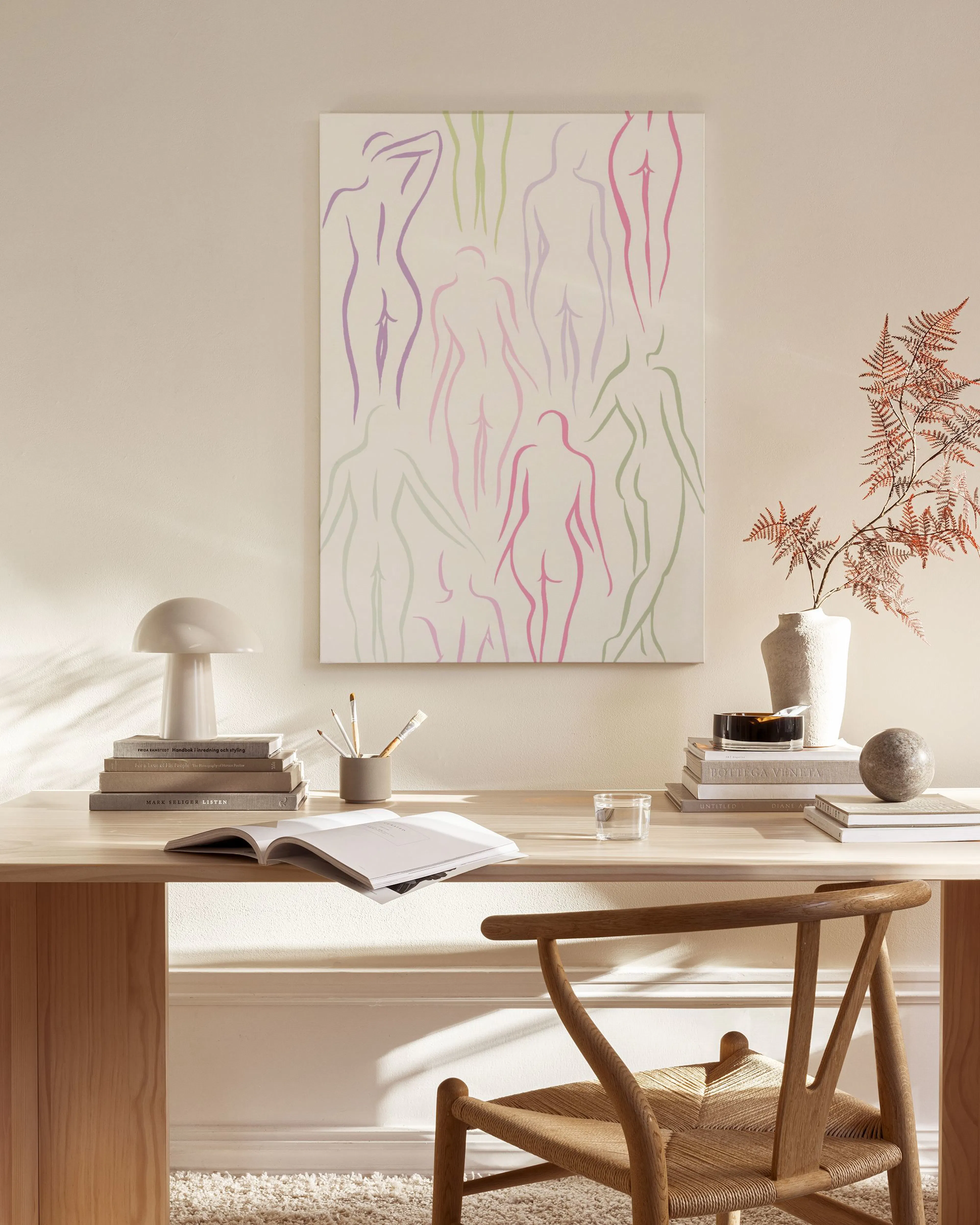 Canvas print with abstract human figures in purple, pink, and green outlines, displayed in a bright, minimalist living room.