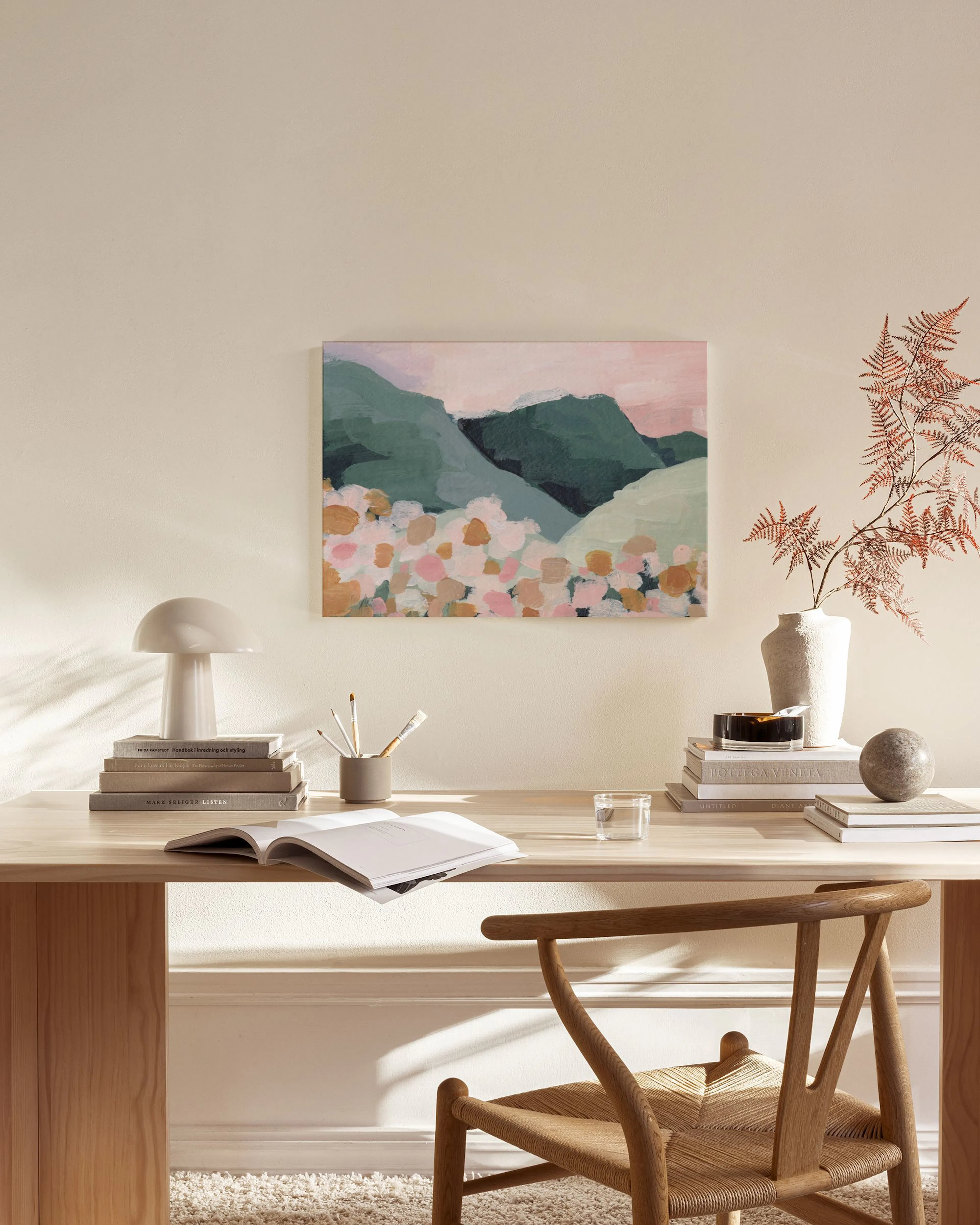 Leinwandbild mit Landschaft in Pastelltönen und grünen Bergen, über einem Holzregal im Wohnzimmer.