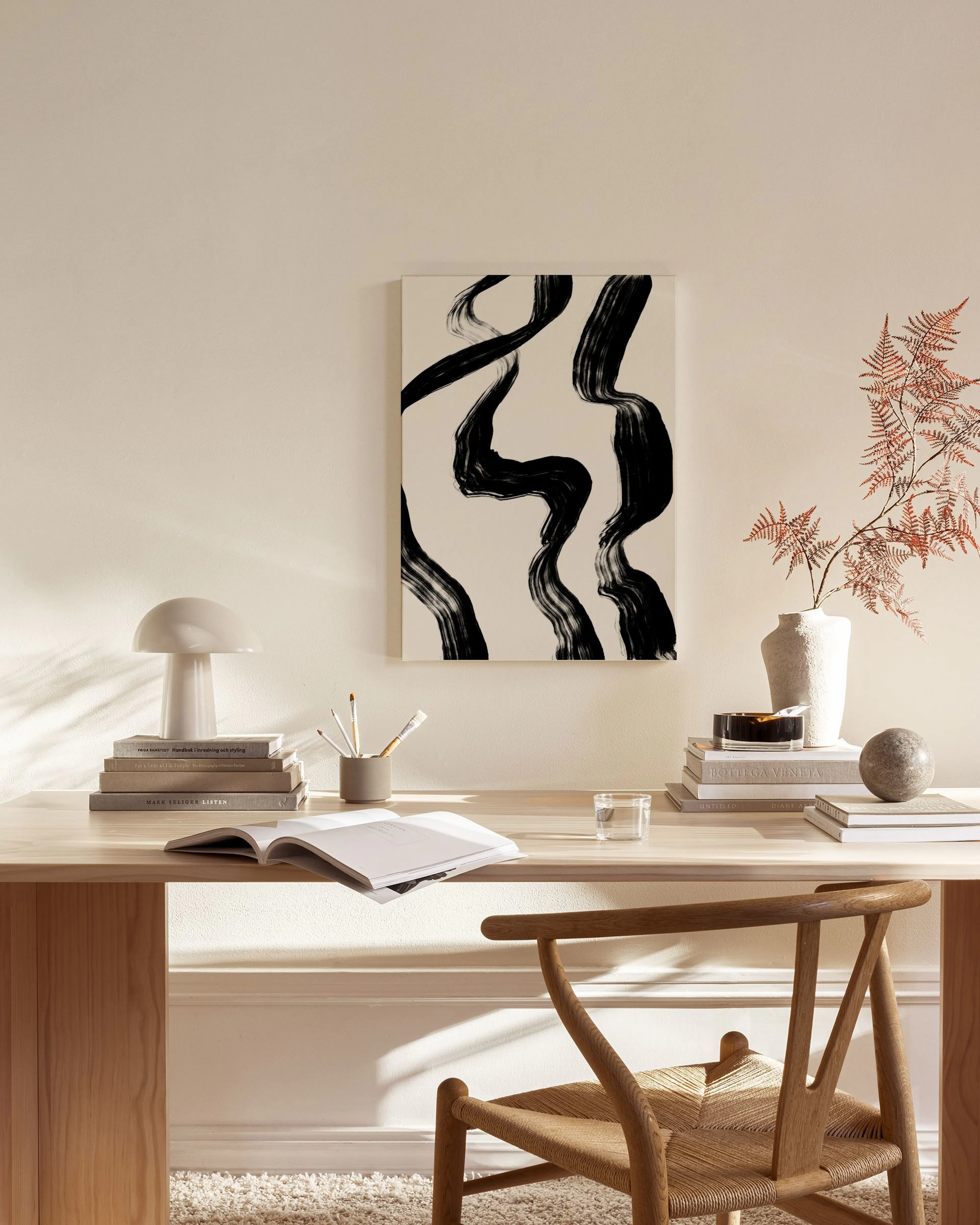 Abstract canvas print with bold black brushstrokes on a light background, hanging in a minimalist living room.