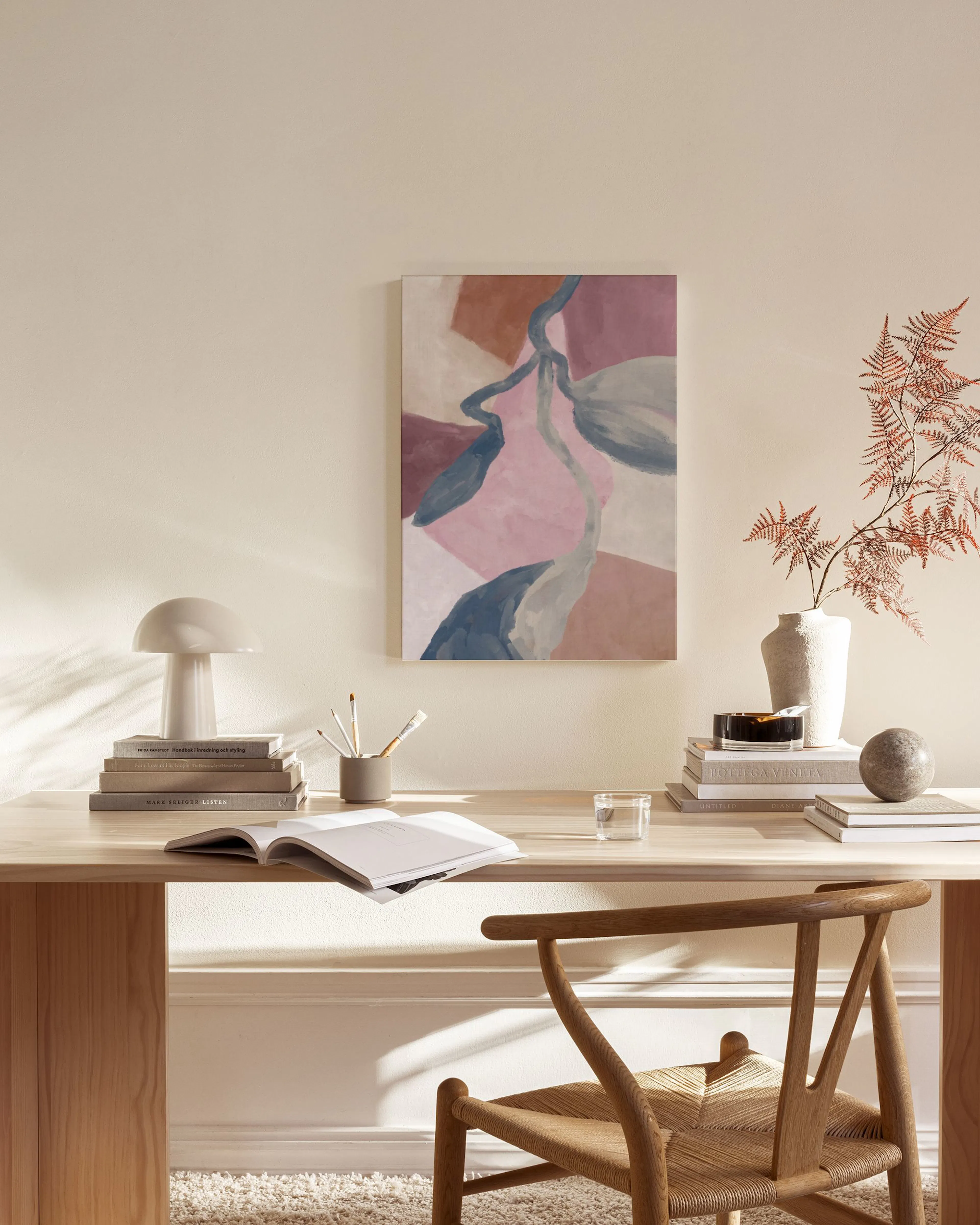 Abstract canvas print with organic shapes in pink, blue, and brown tones, hanging in a minimalist living room.