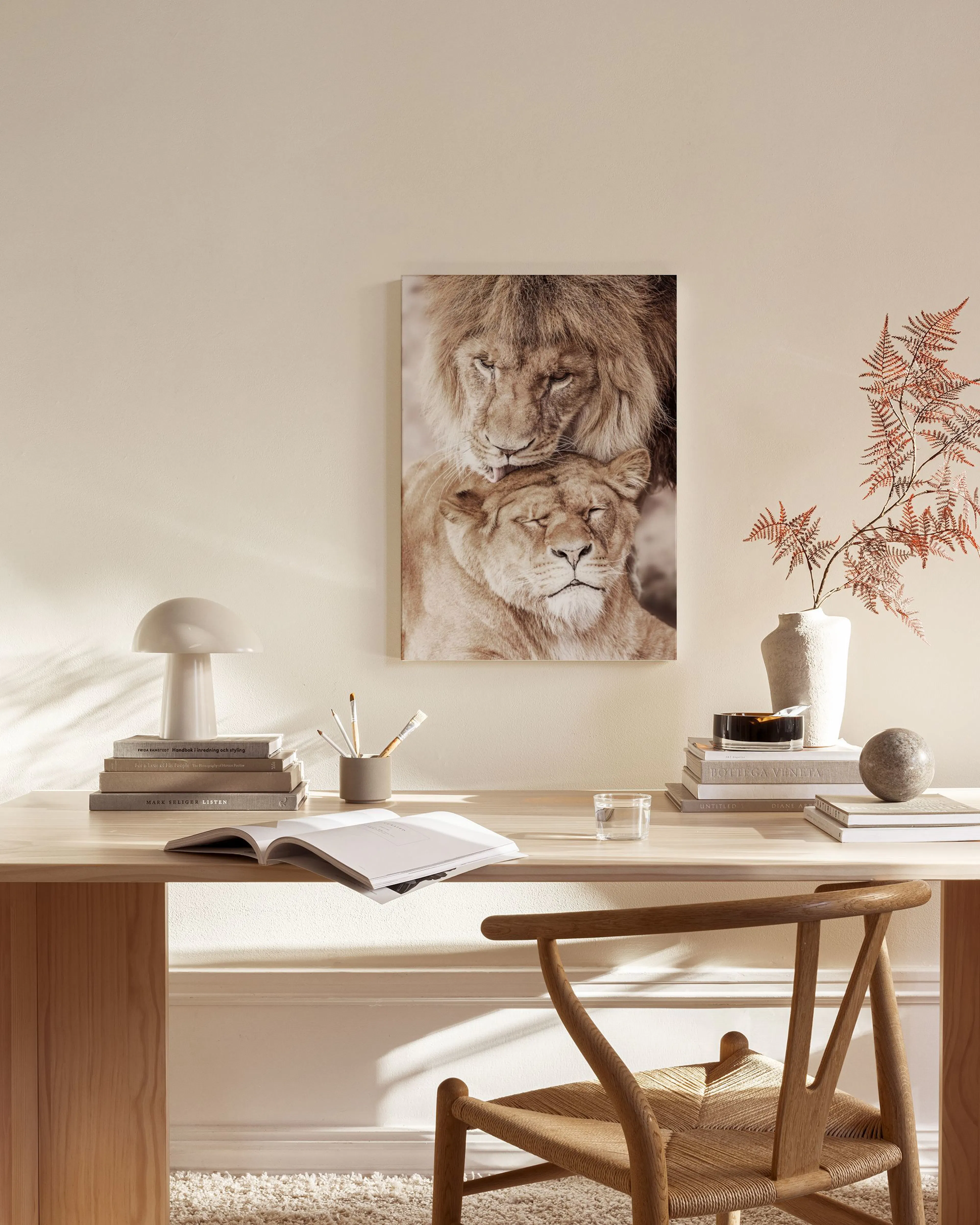 Stampa su tela di due leoni in stile seppia, appesa in un soggiorno moderno sopra una panca in legno.