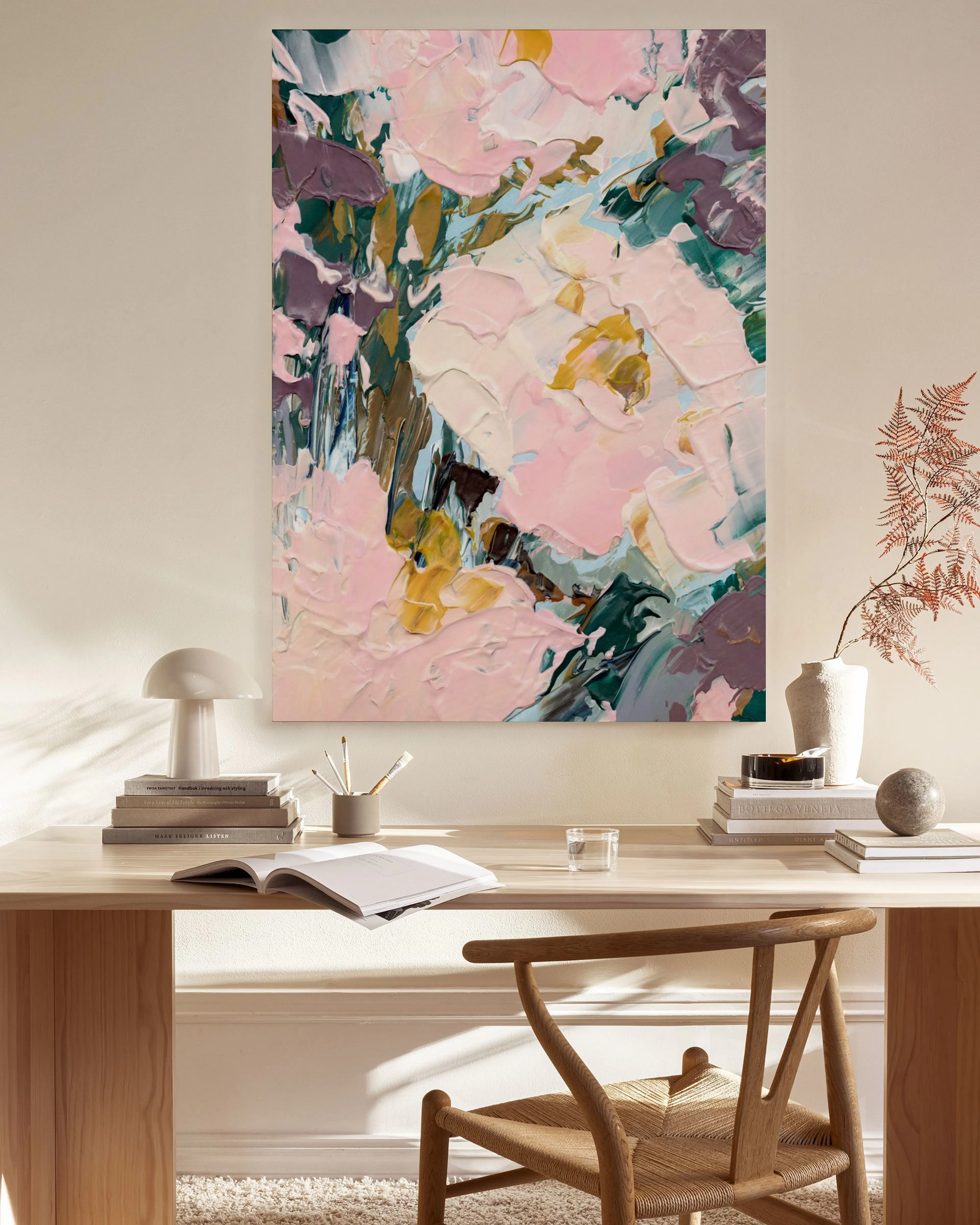 Stampa su tela con fiori astratti rosa e gialli, appesa in un soggiorno moderno sopra una panca in legno.