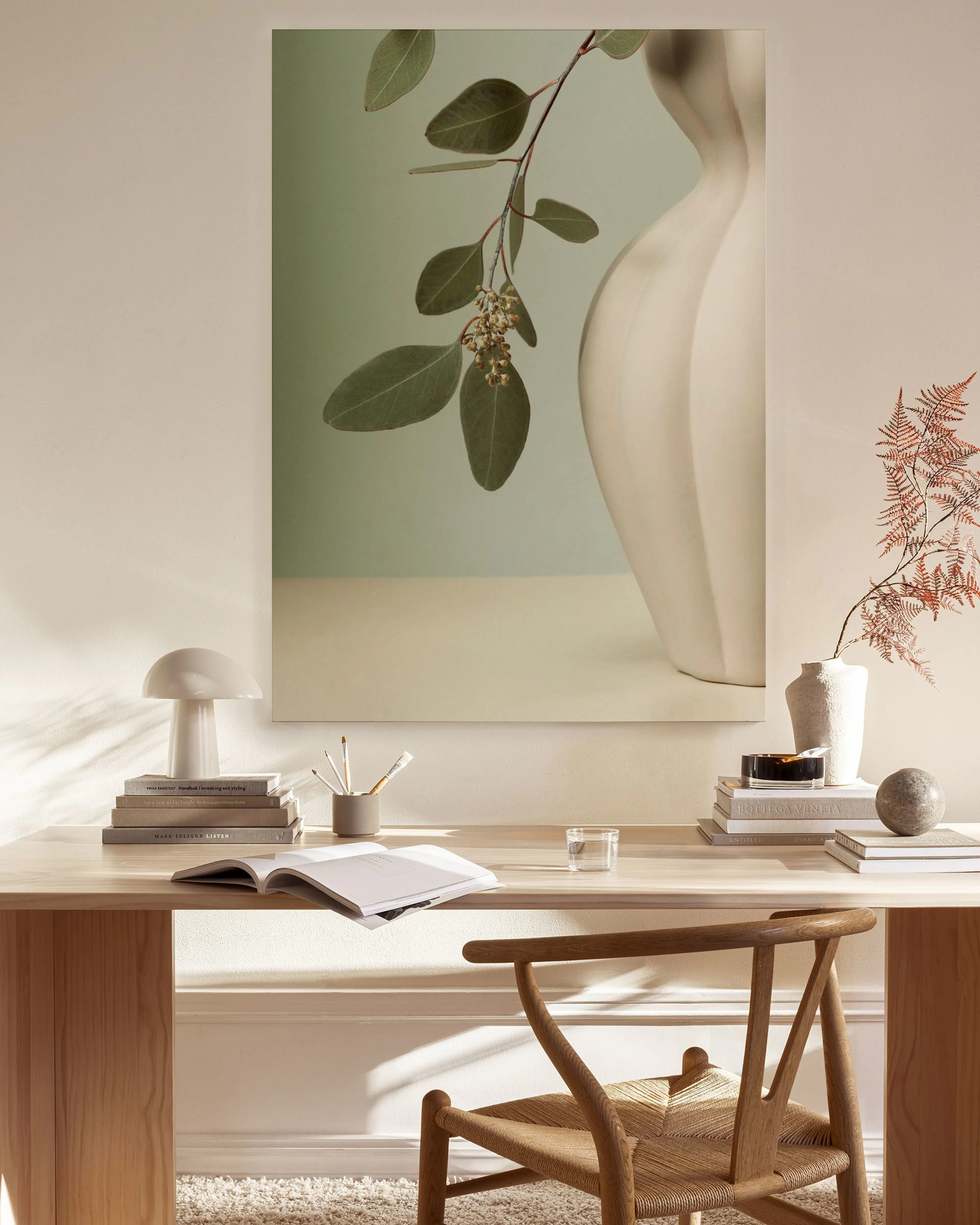 A canvas print of eucalyptus branches with leaves and buds in a cream ridged vase, on a minimalist sage green and beige backgrou