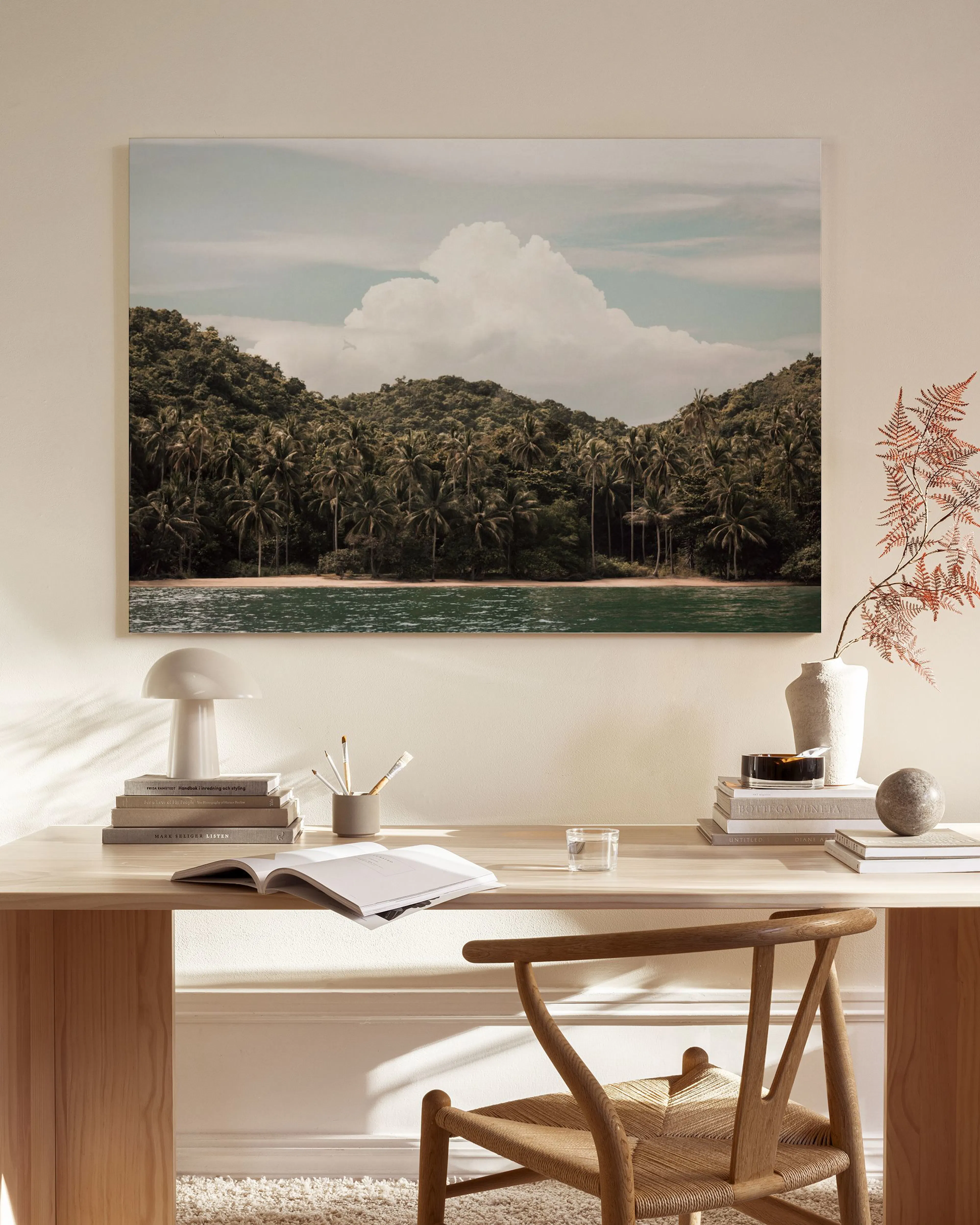Tropical canvas print of a lush green palm tree island and blue water, hanging in a modern living room.