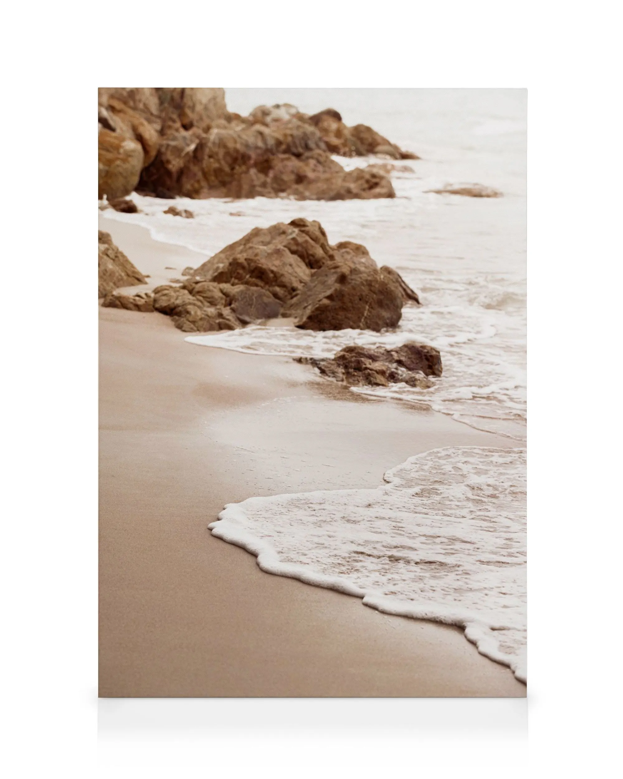 Lienzo de una tranquila playa rocosa con olas espumosas que llegan a la orilla de arena clara.