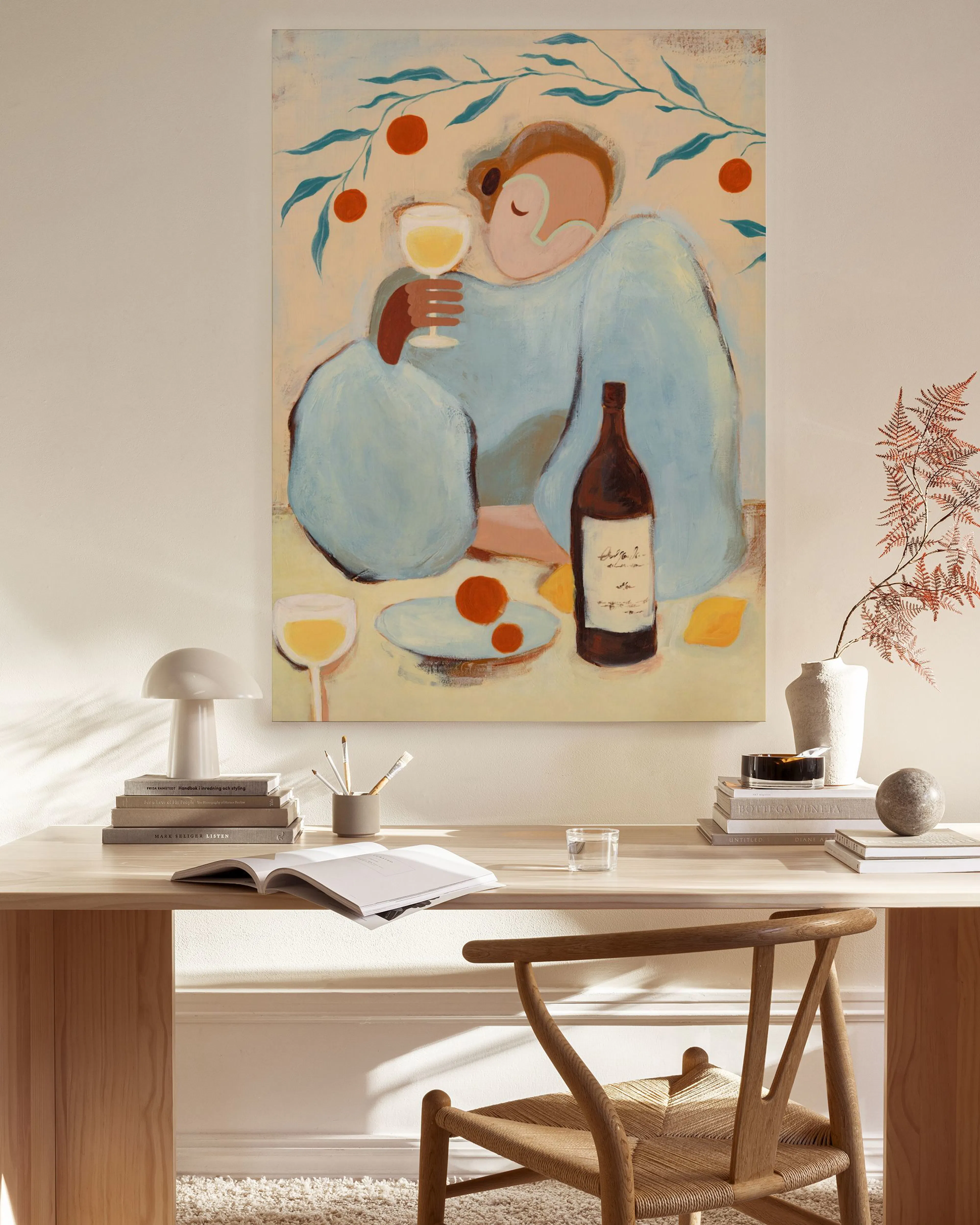Toile dun personnage buvant du vin, avec des oranges et une bouteille, accrochée dans un salon lumineux.