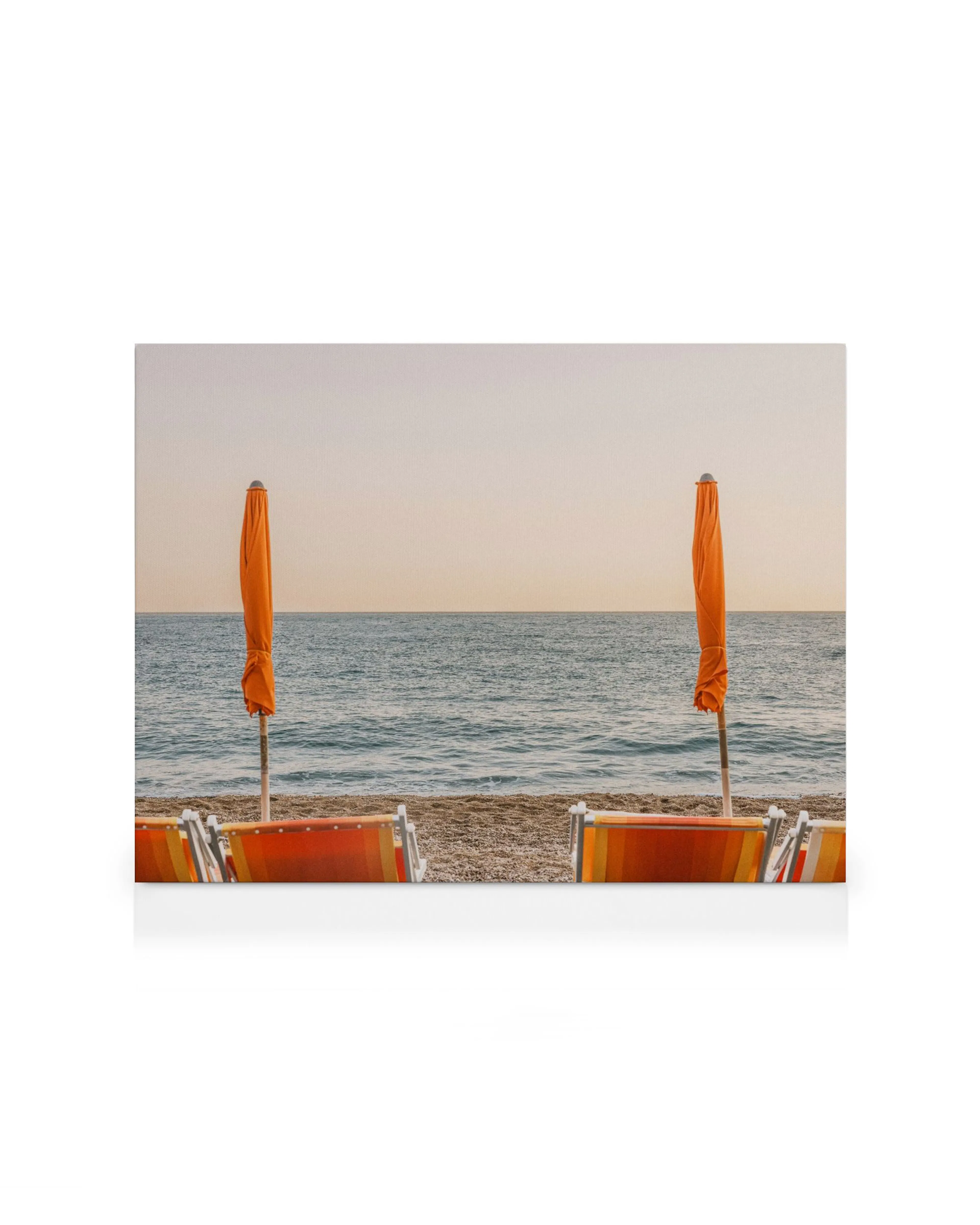 Tela decorativa com duas cadeiras de praia e guarda-sóis laranja fechados, virados para o mar num dia de sol.