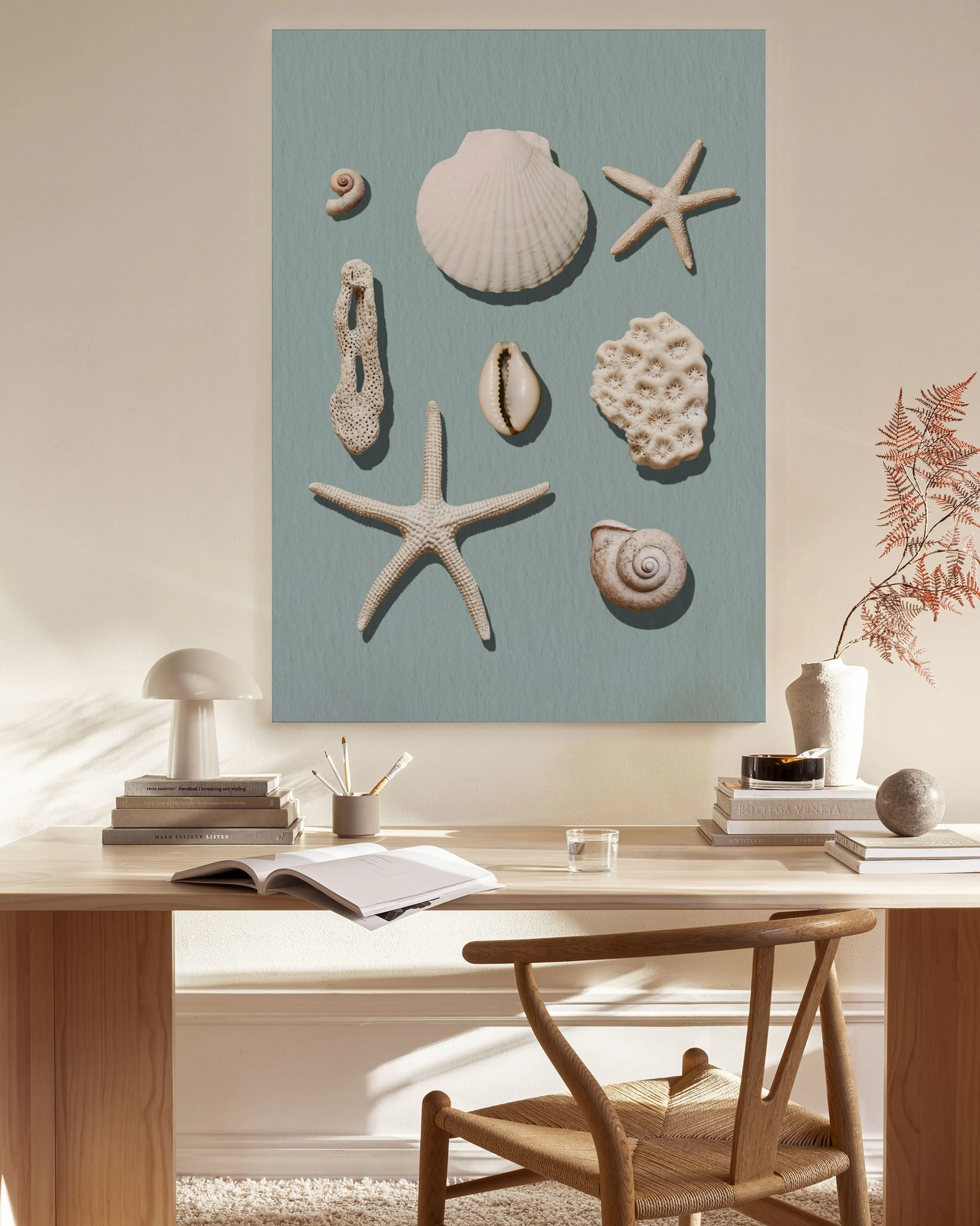 Leinwandbild mit Muscheln und Seesternen auf hellblauem Grund, im Wohnzimmer über einem Sideboard.