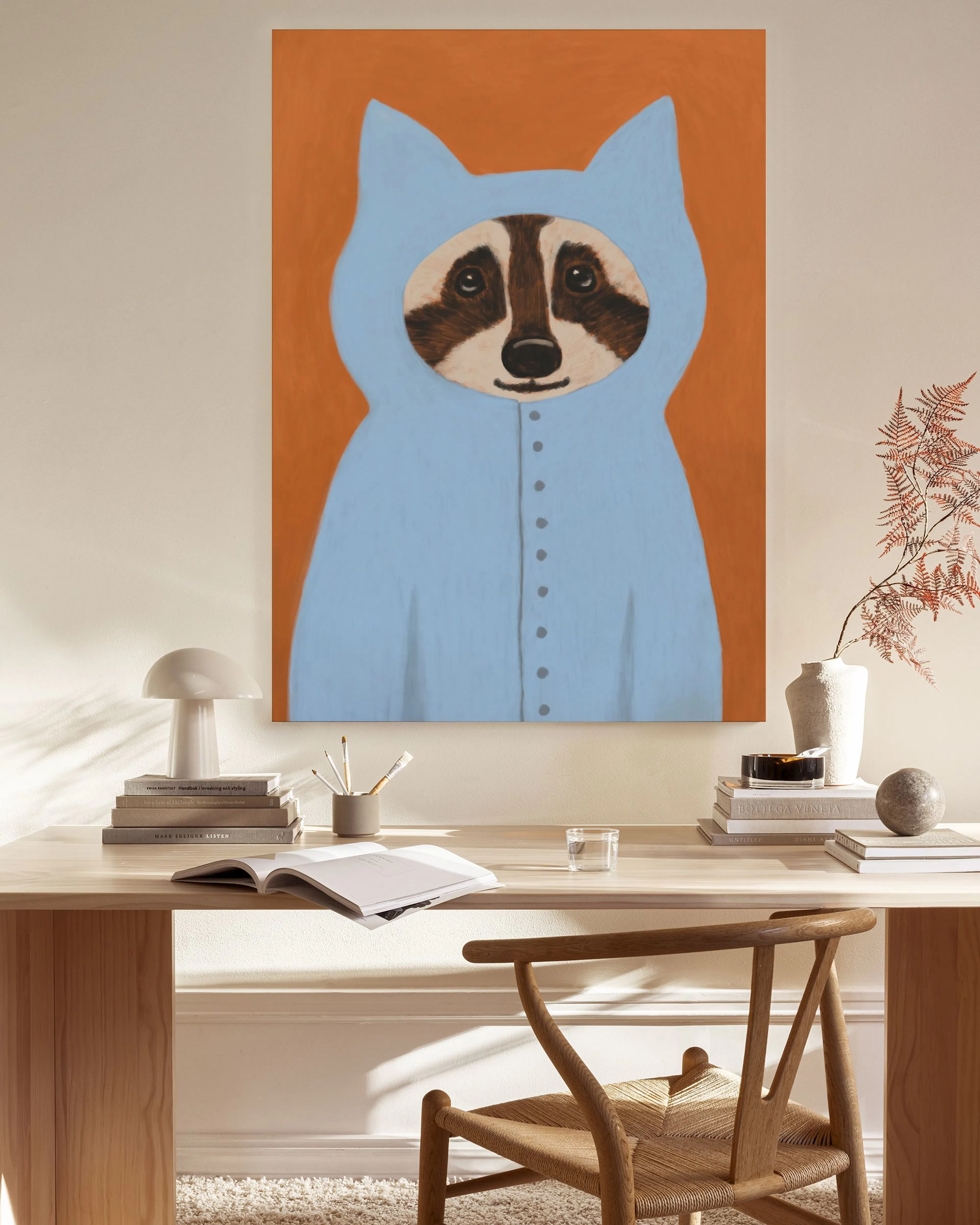 Leinwandbild mit einem Waschbären im blauen Kostüm, hängend in einem hellen Wohnzimmer über einer Holzbank.
