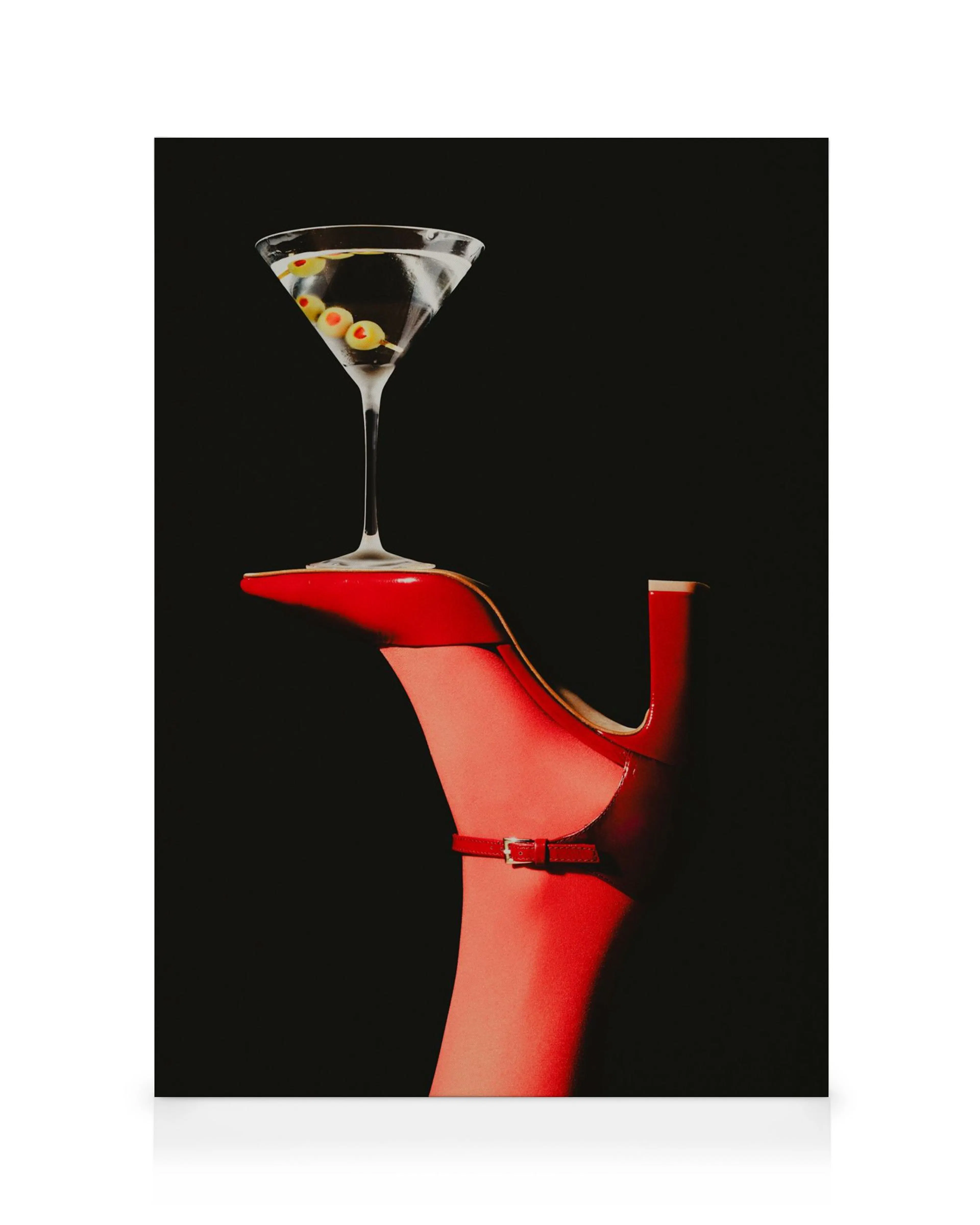 Toile présentant un verre à martini posé sur un talon aiguille rouge, sur fond noir