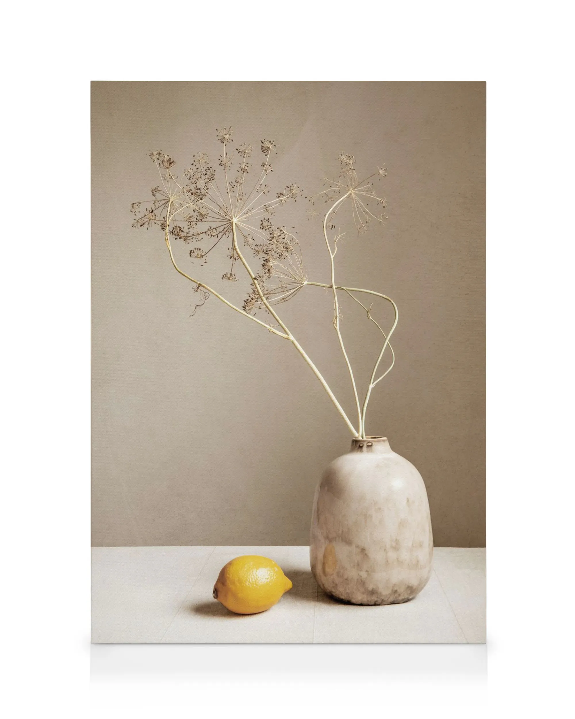 Leinwandbild: Braune Vase mit getrockneten Pflanzen und leuchtend gelber Zitrone auf beigem Hintergrund, erdiger Stil.