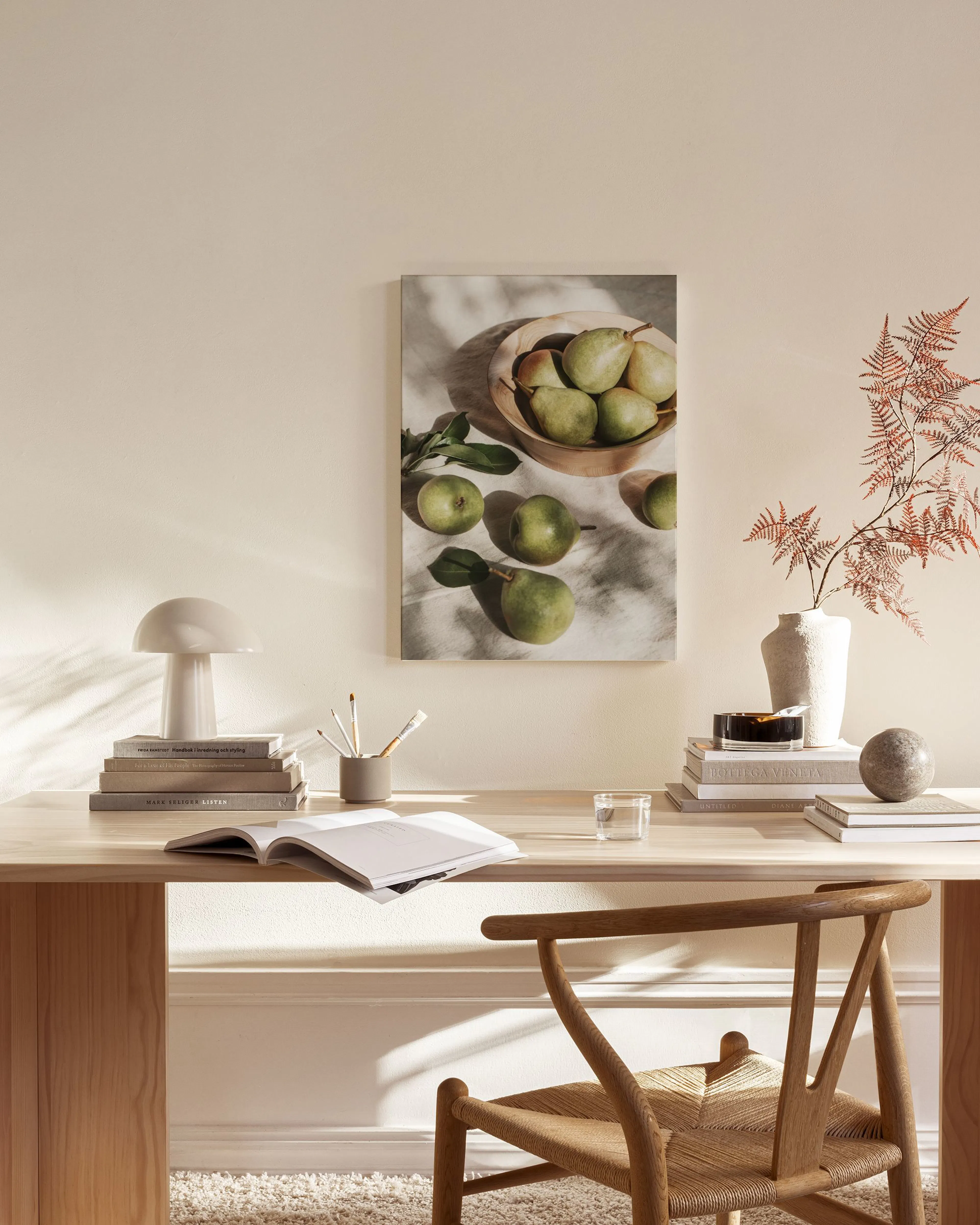 Canvas met peren in een houten kom en losse peren, hangend in een neutrale woonkamer boven een dressoir.