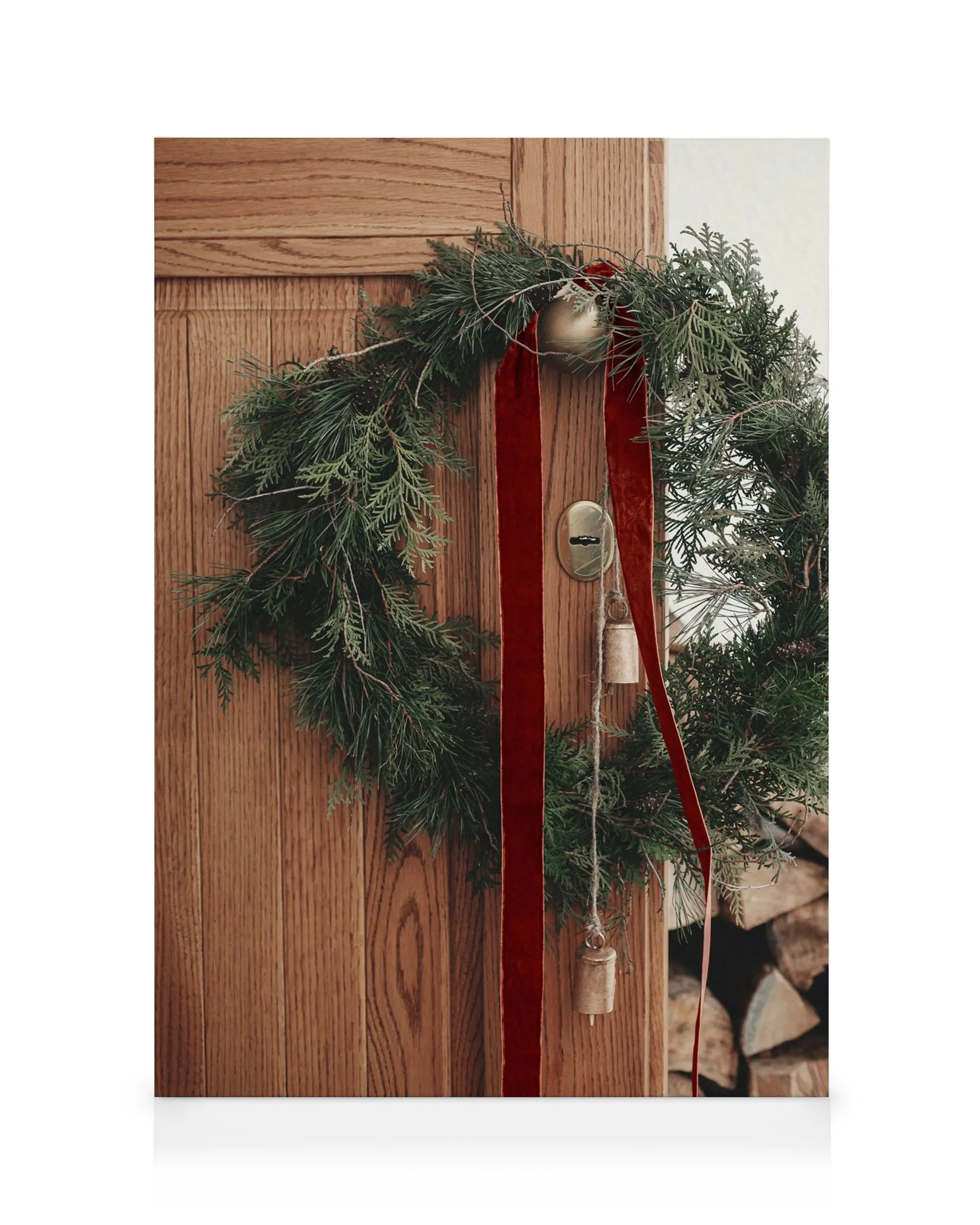 Ghirlanda natalizia rustica su porta in legno, nastro rosso velluto, campane dorate, decorazione festiva.