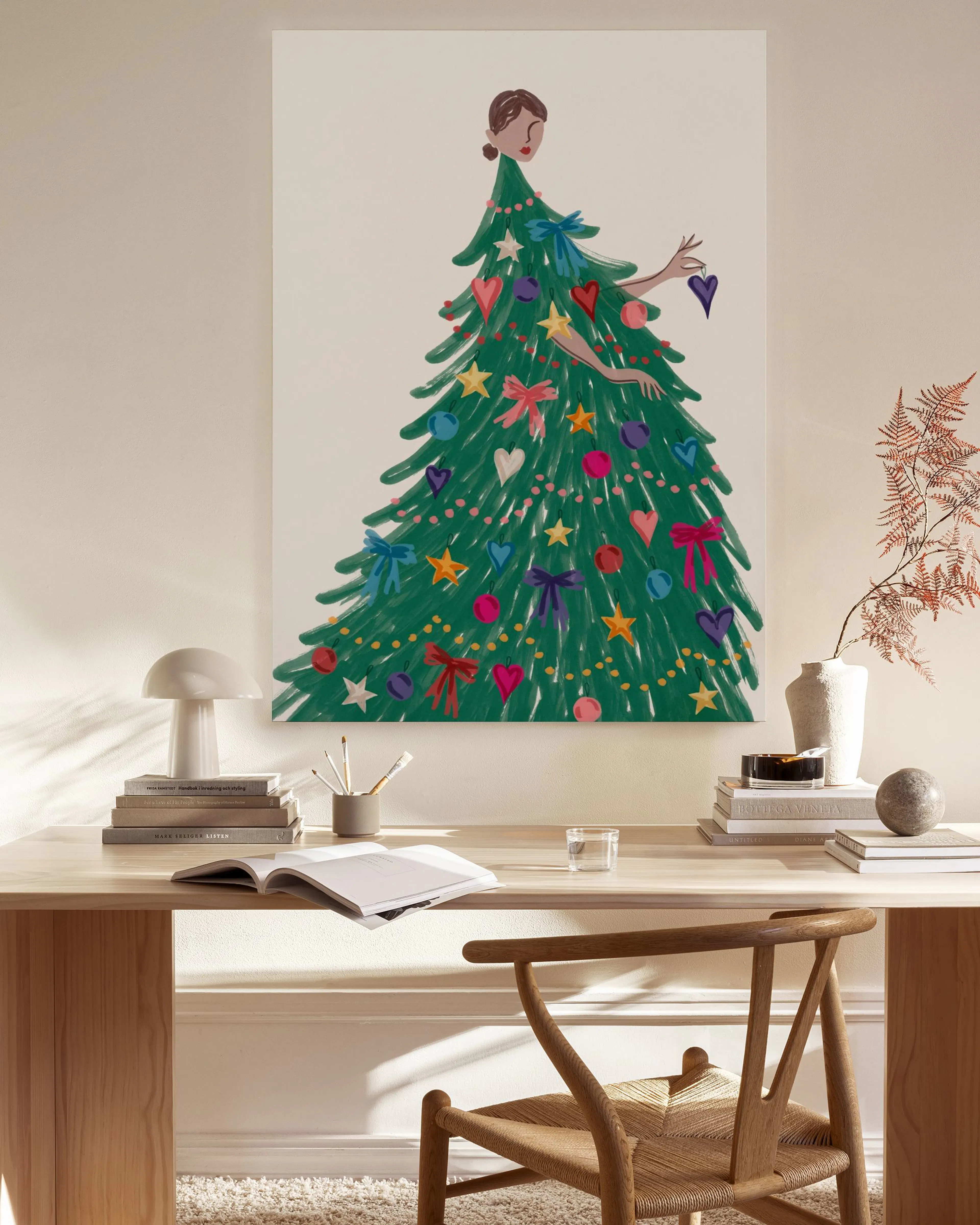 Tela decorativa de uma mulher vestida de árvore de Natal com laços e corações, exposta numa sala de estar minimalista com móveis