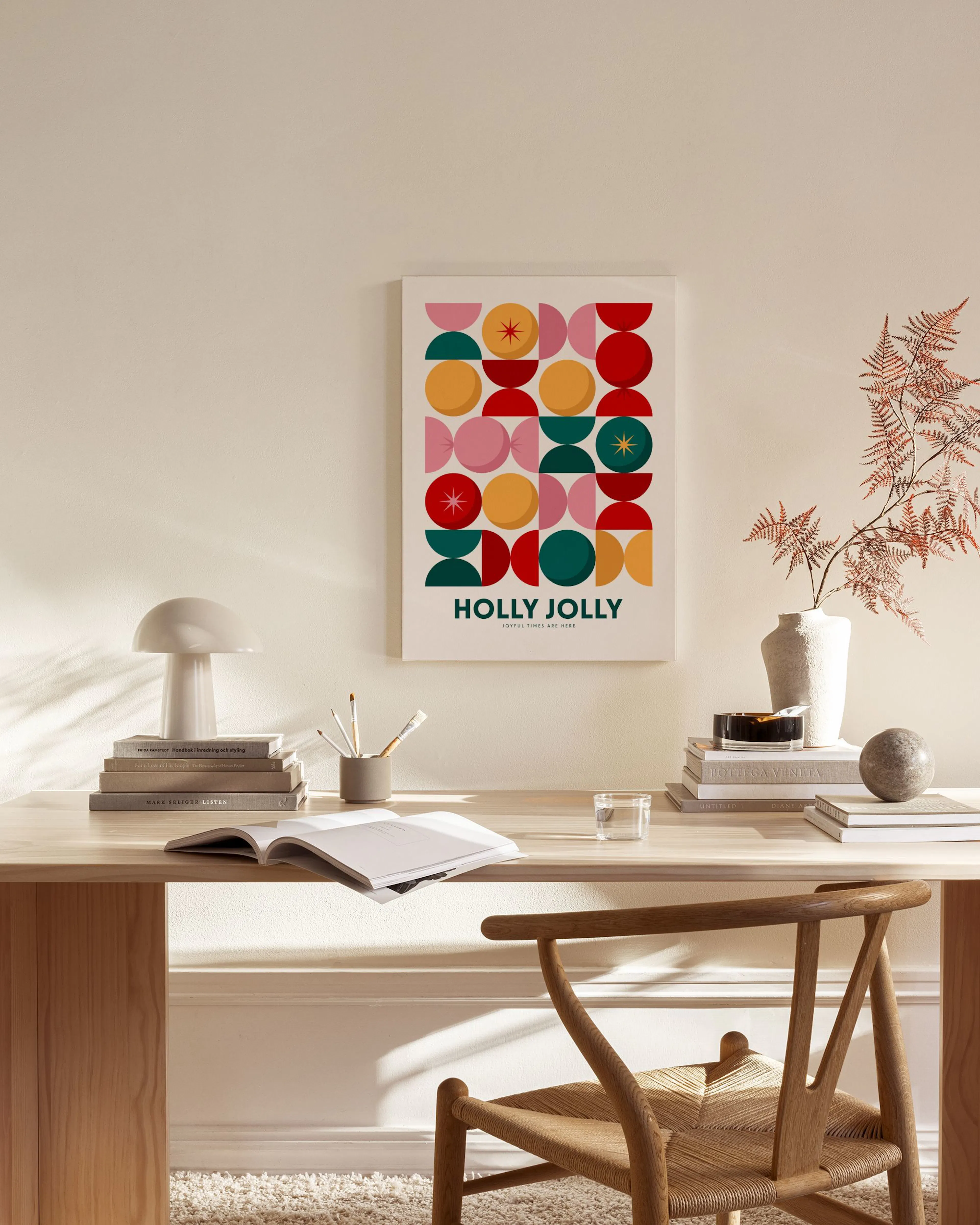 A canvas print with a Holly Jolly geometric pattern in red, pink, yellow, and teal, displayed in a bright living room above a wo