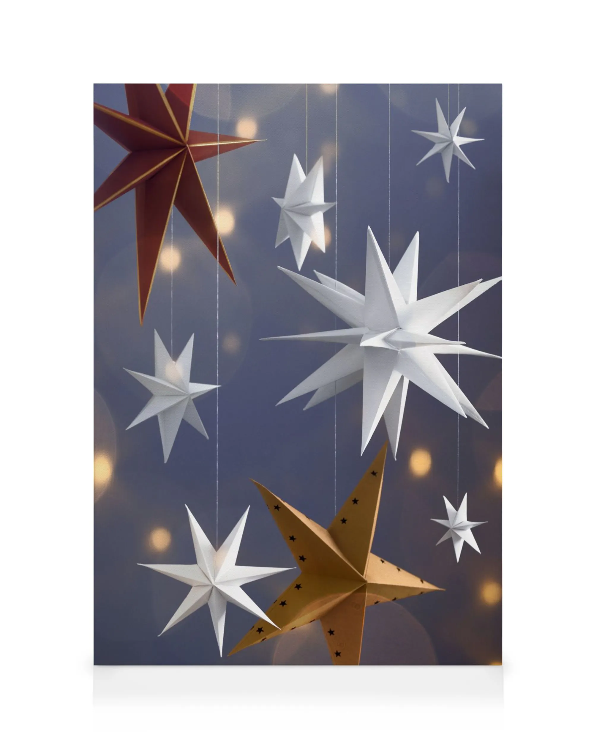 Stampa su tela con decorazioni di stelle bianche, rosse e dorate appese su sfondo blu con luci bokeh.