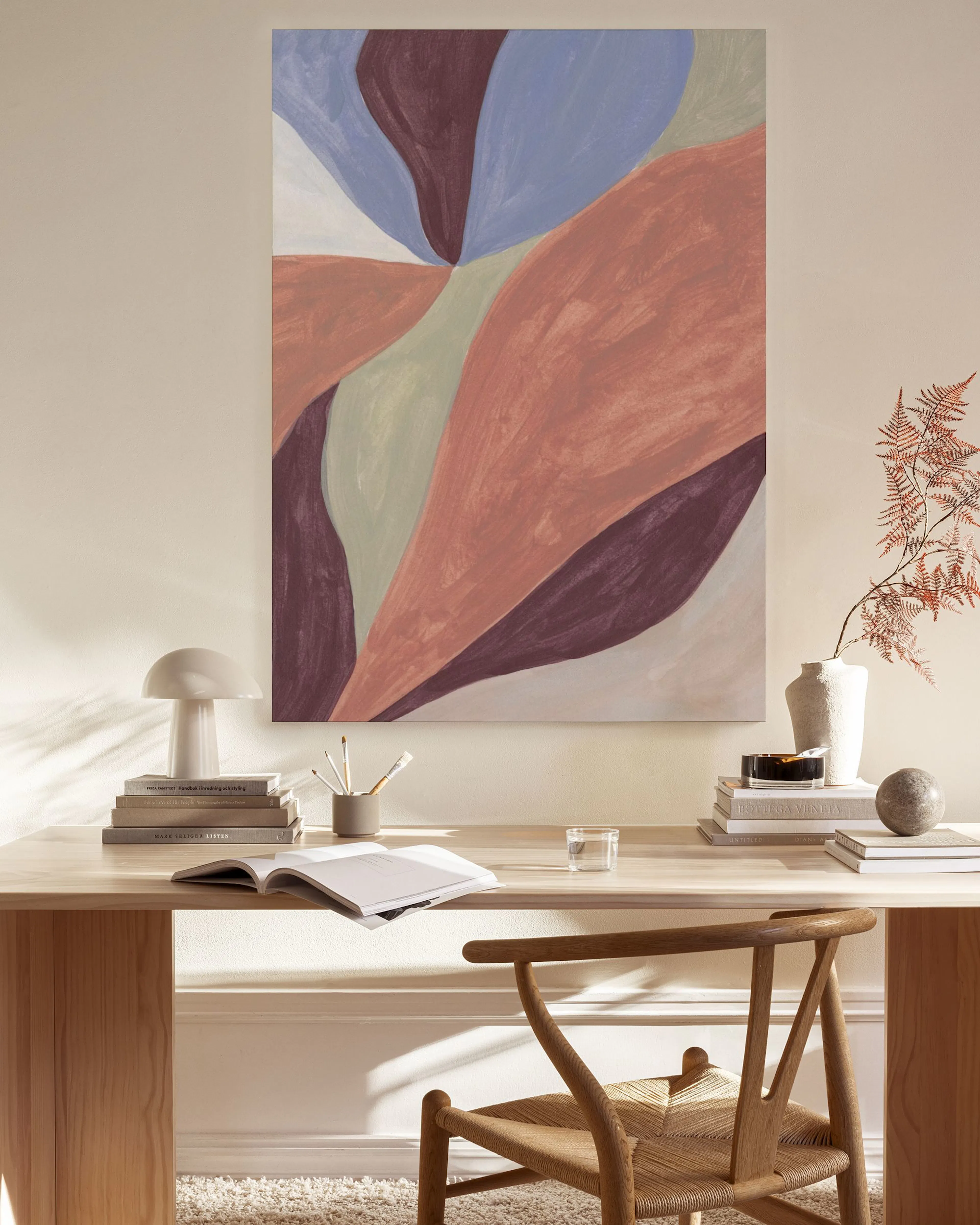 Stampa su tela astratta con forme organiche blu, rosa e bordeaux appesa in un soggiorno moderno.
