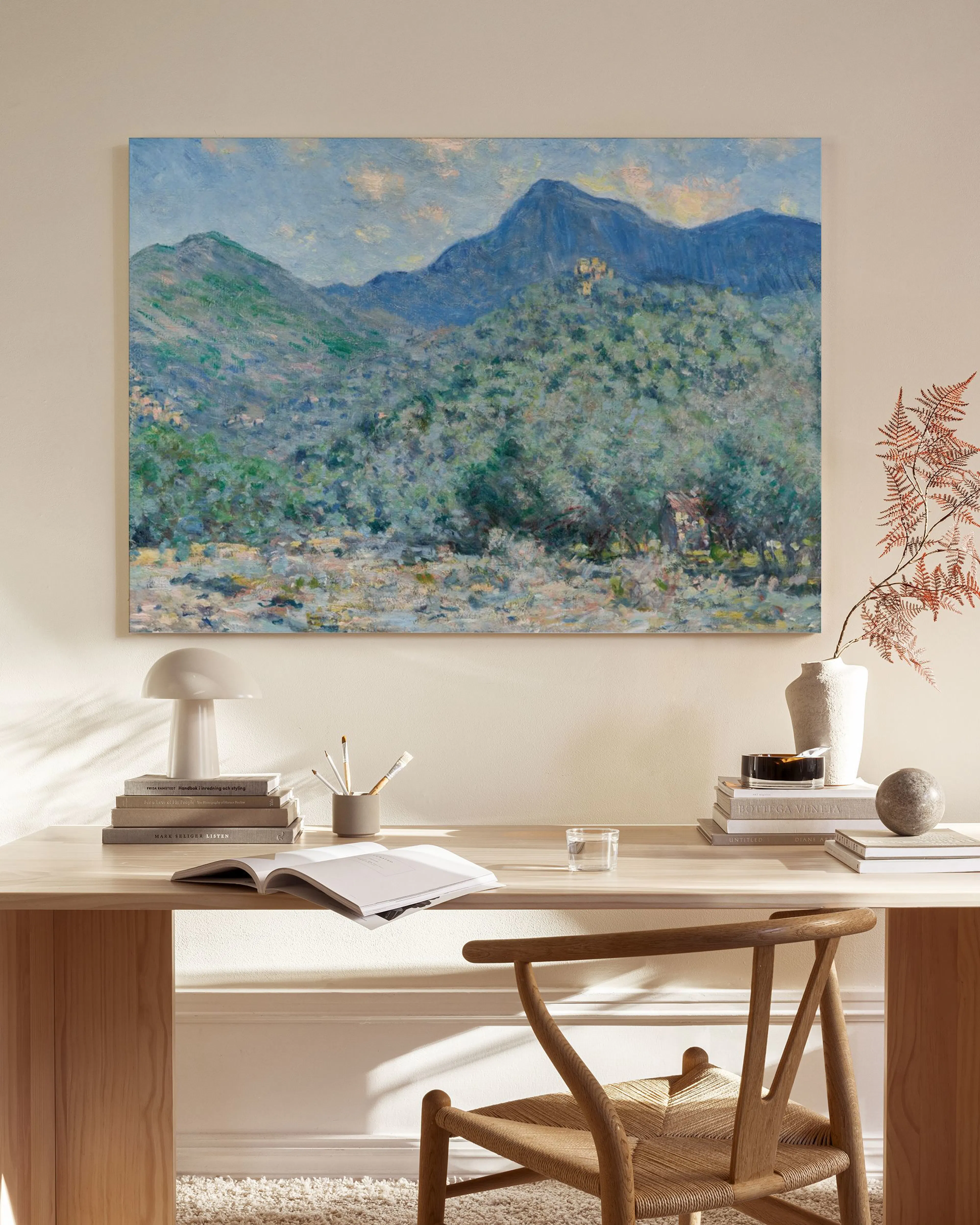 Impressionist canvas print of green and blue mountains with a river, hanging in a modern living room.