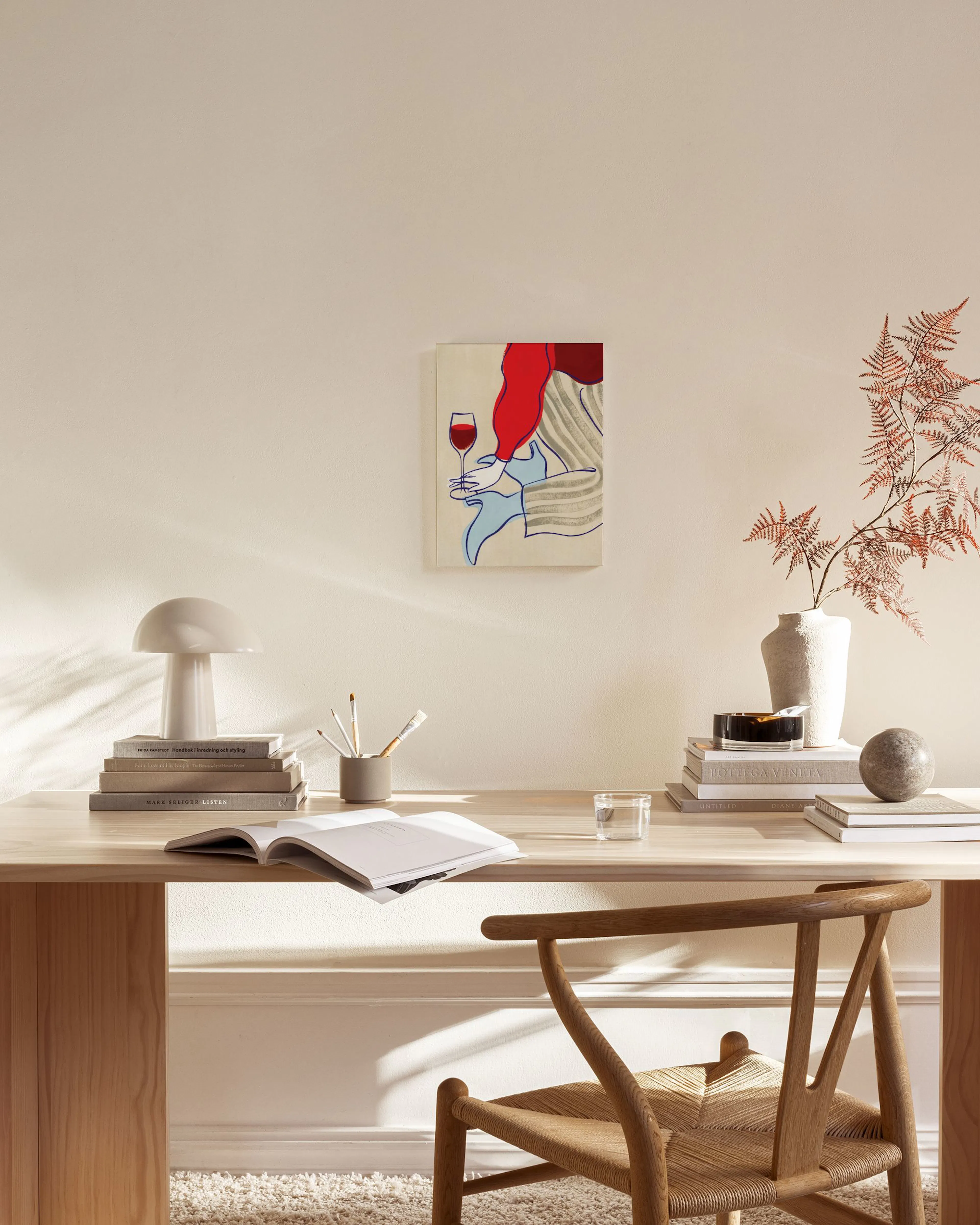 Lienzo de mujer abstracta con blusa roja y copa de vino, colgado sobre un mueble bajo en una sala.