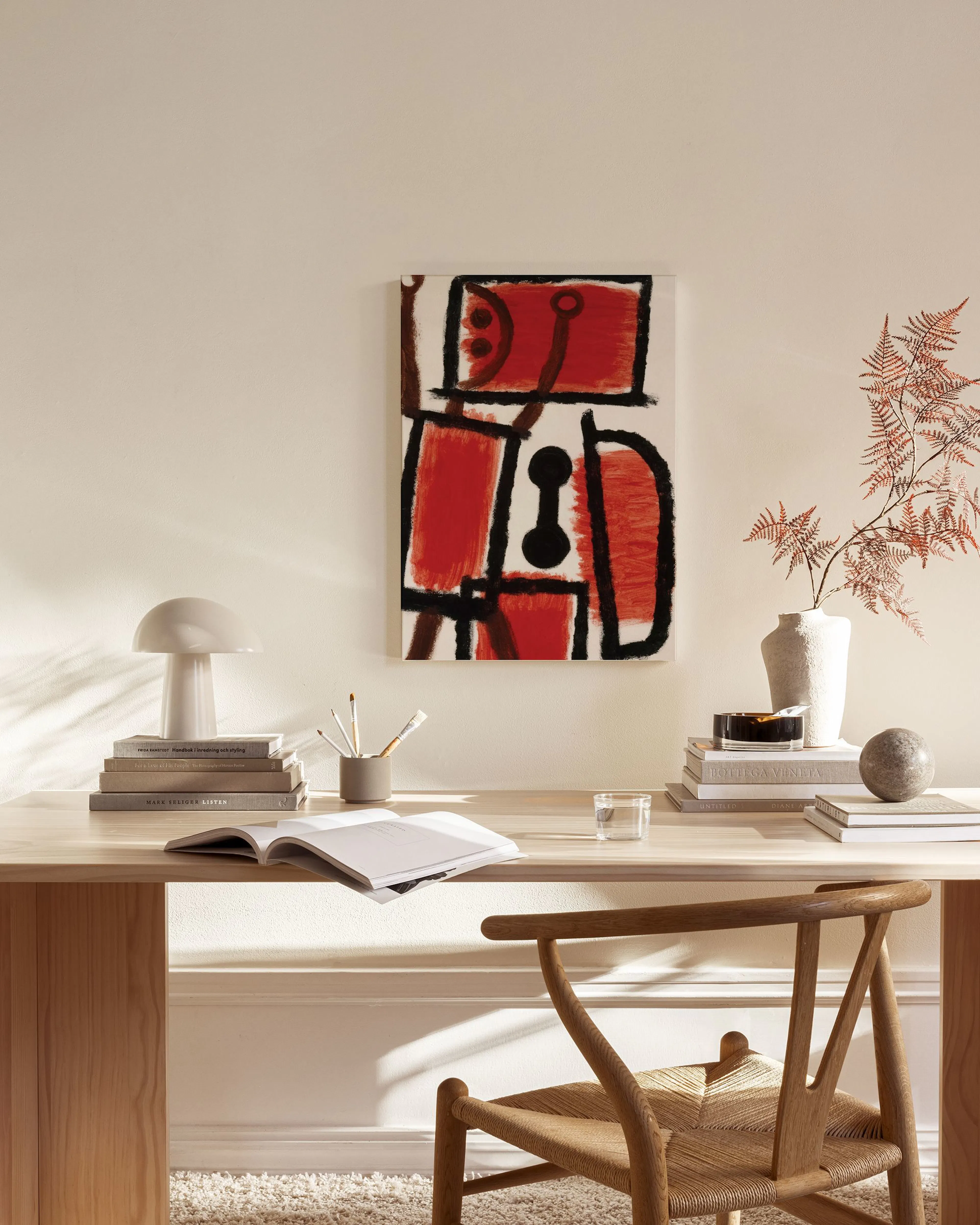Abstract canvas print with red, black, and white organic shapes, hanging in a minimalist living room with a light wood chair.