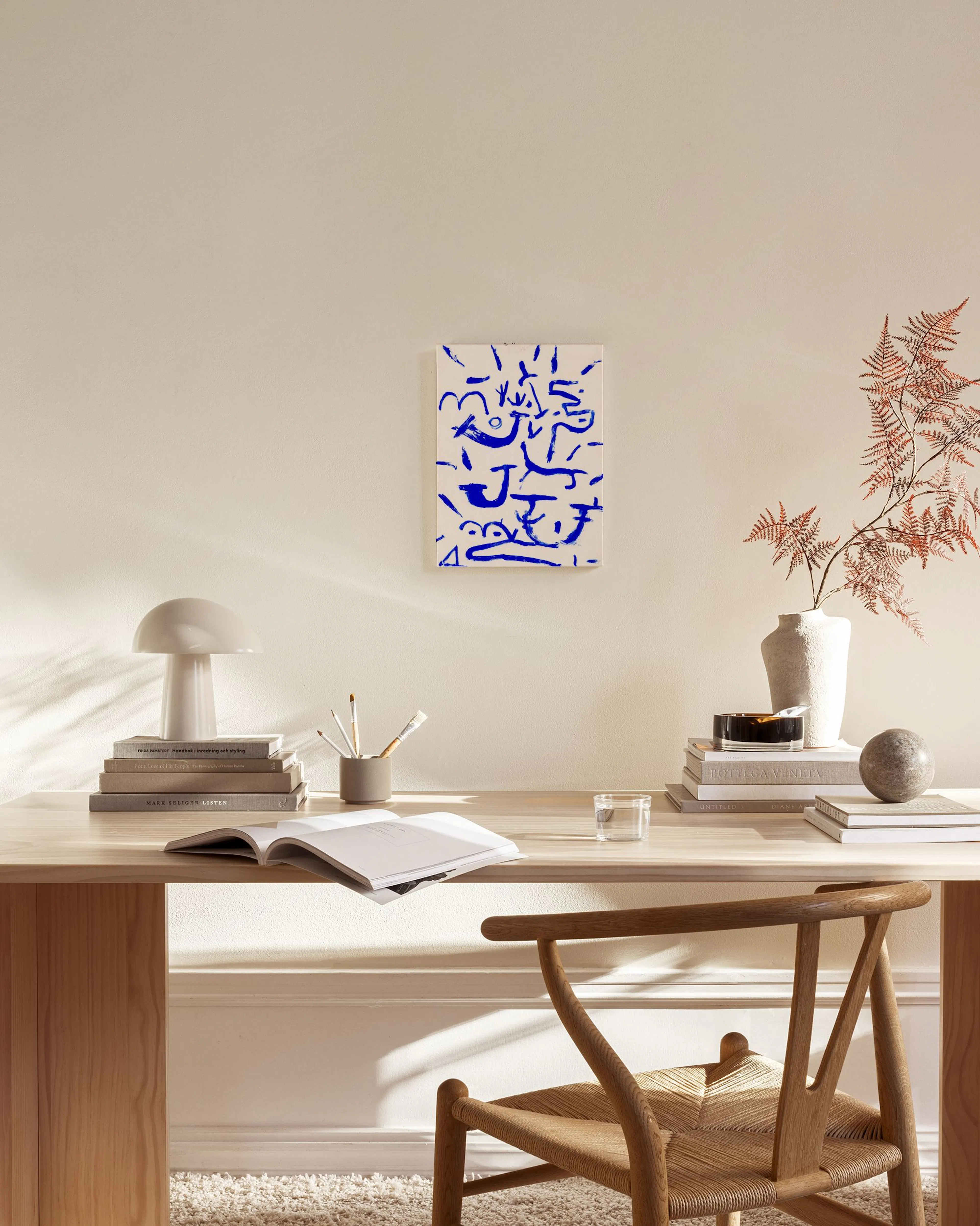 Canvas met blauwe organische vormen en lijnen op een lichte achtergrond, hangend in een moderne woonkamer.