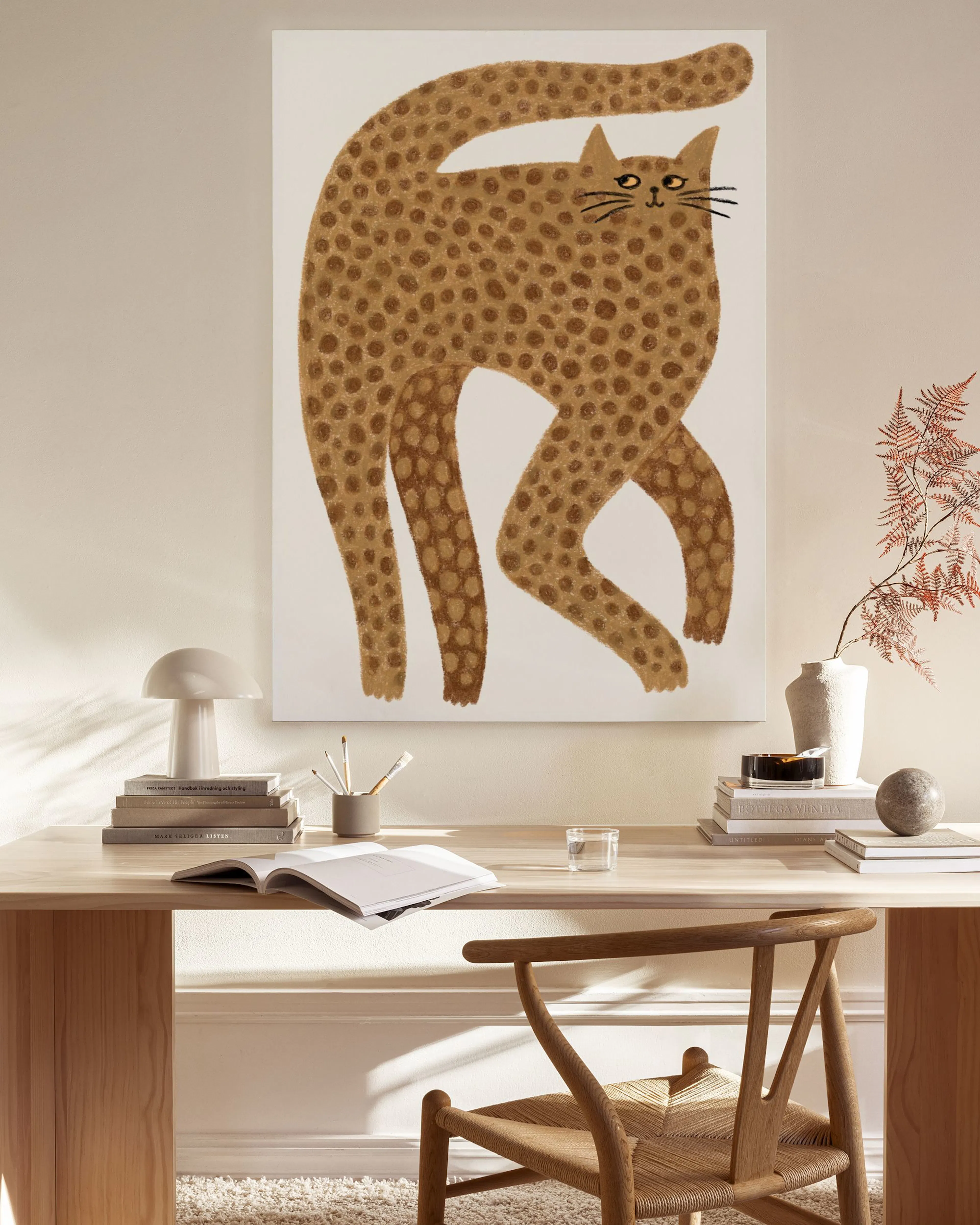 Canvastavla med en brun leopardmönstrad katt som sträcker sig, hängande i ett ljust vardagsrum.