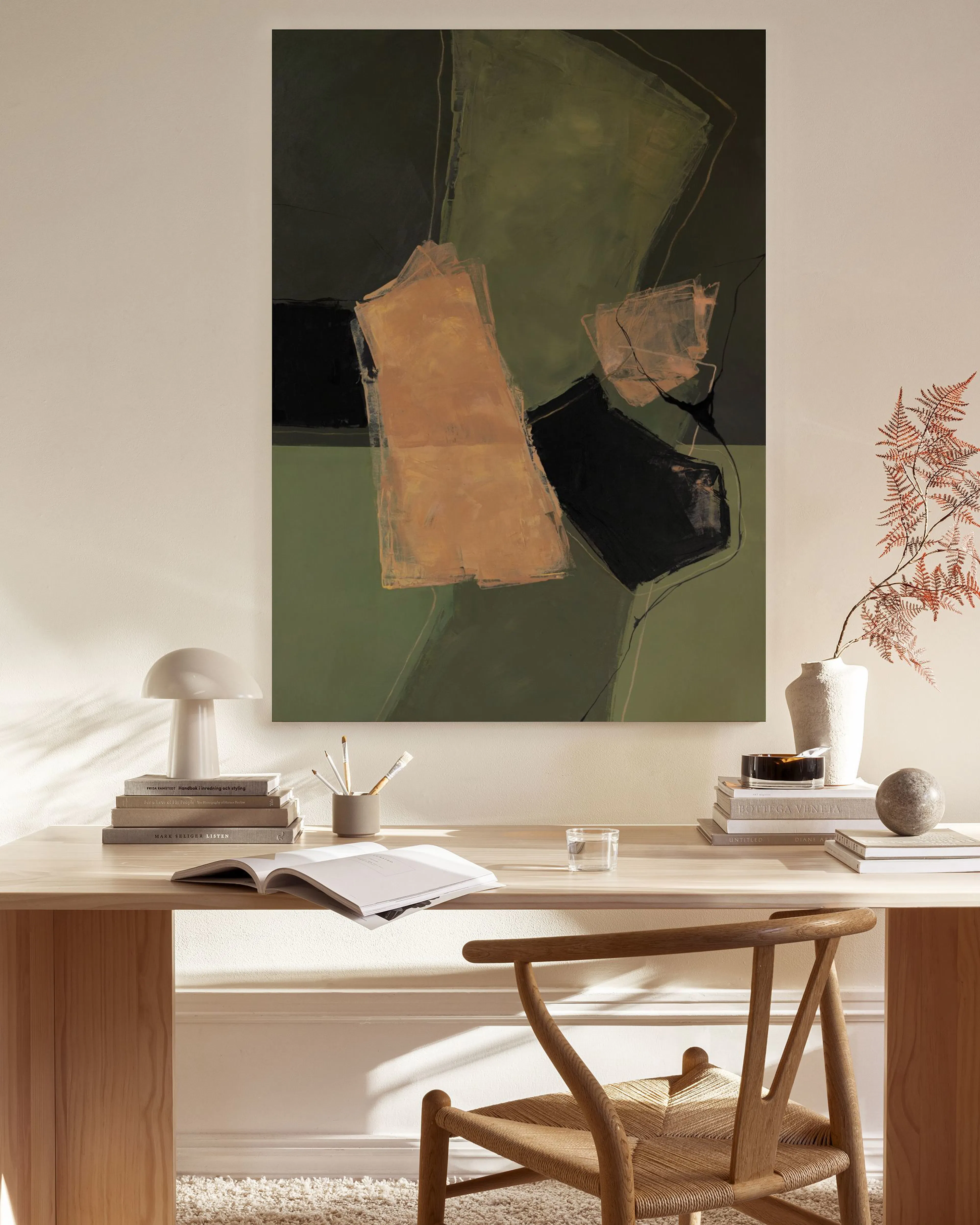 Abstract canvas print with green, black, and tan shapes, hanging above a wooden console in a living room.