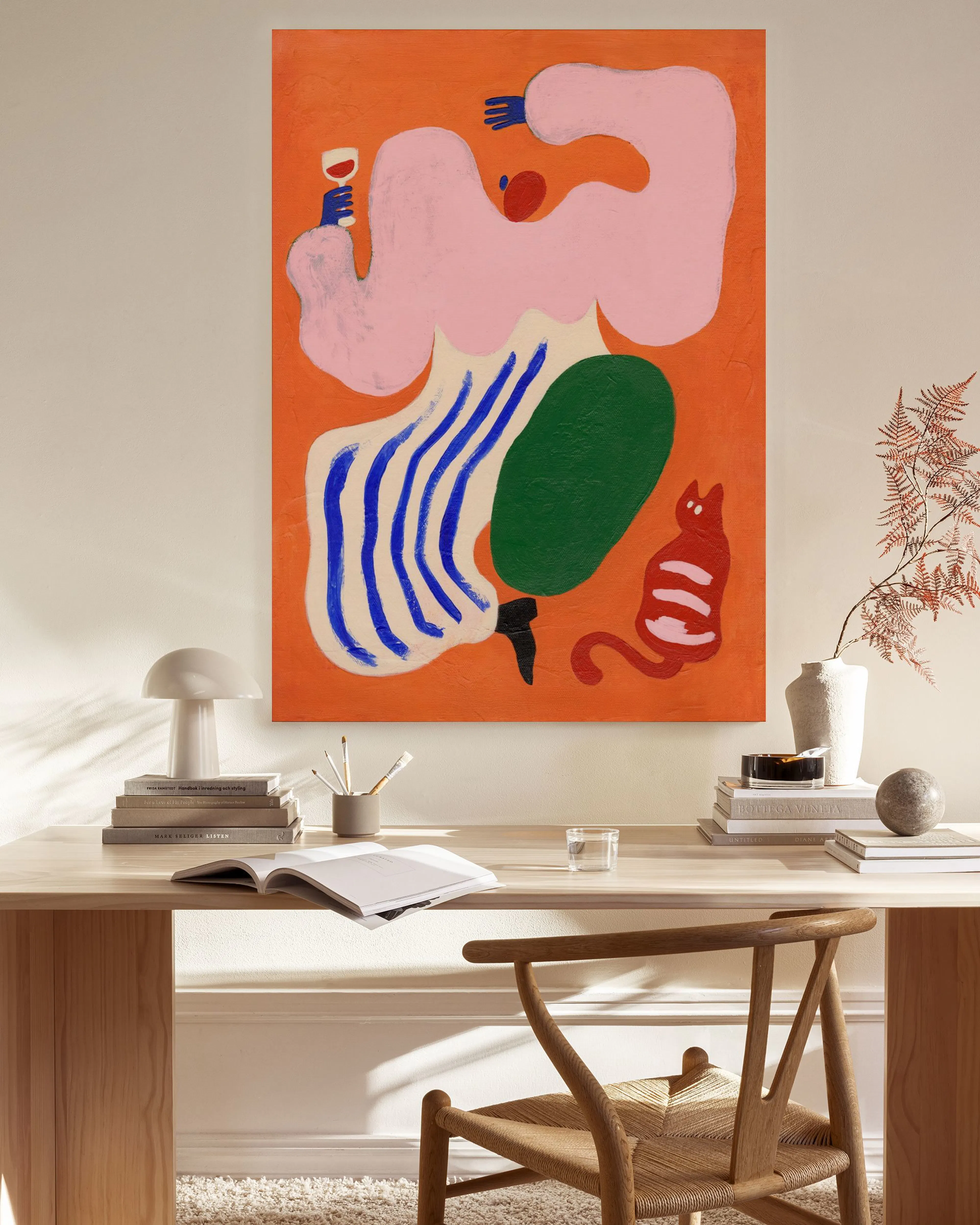 Lærred med abstrakt kunst af lyserøde, blå og grønne former samt en rød kat, hængende i en stue.