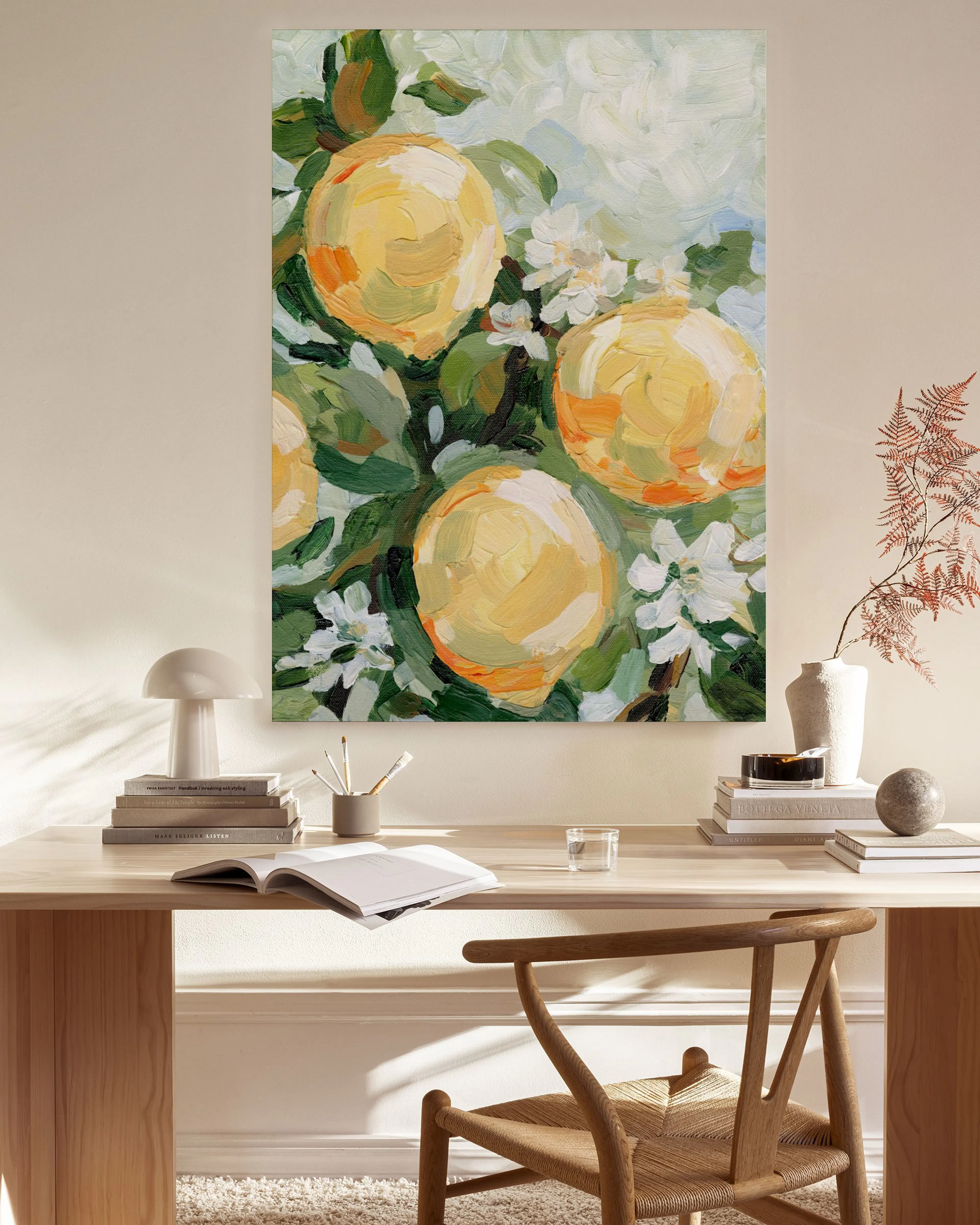 Stampa su tela di limoni gialli e fiori bianchi, appesa sopra una panca in un salotto moderno.