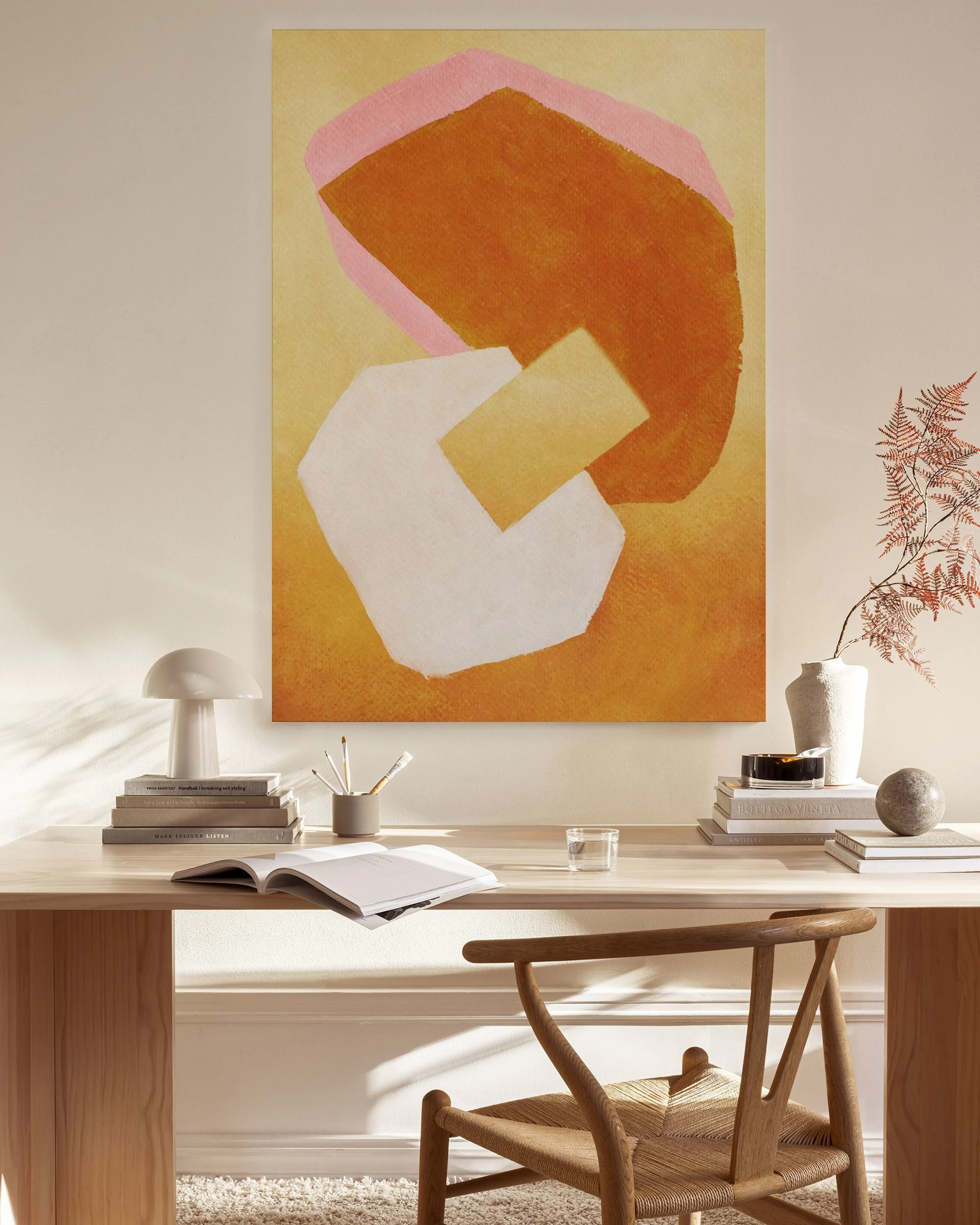 Een canvas met abstracte oranje en roze vormen en een witte vlek, hangend in een moderne woonkamer.