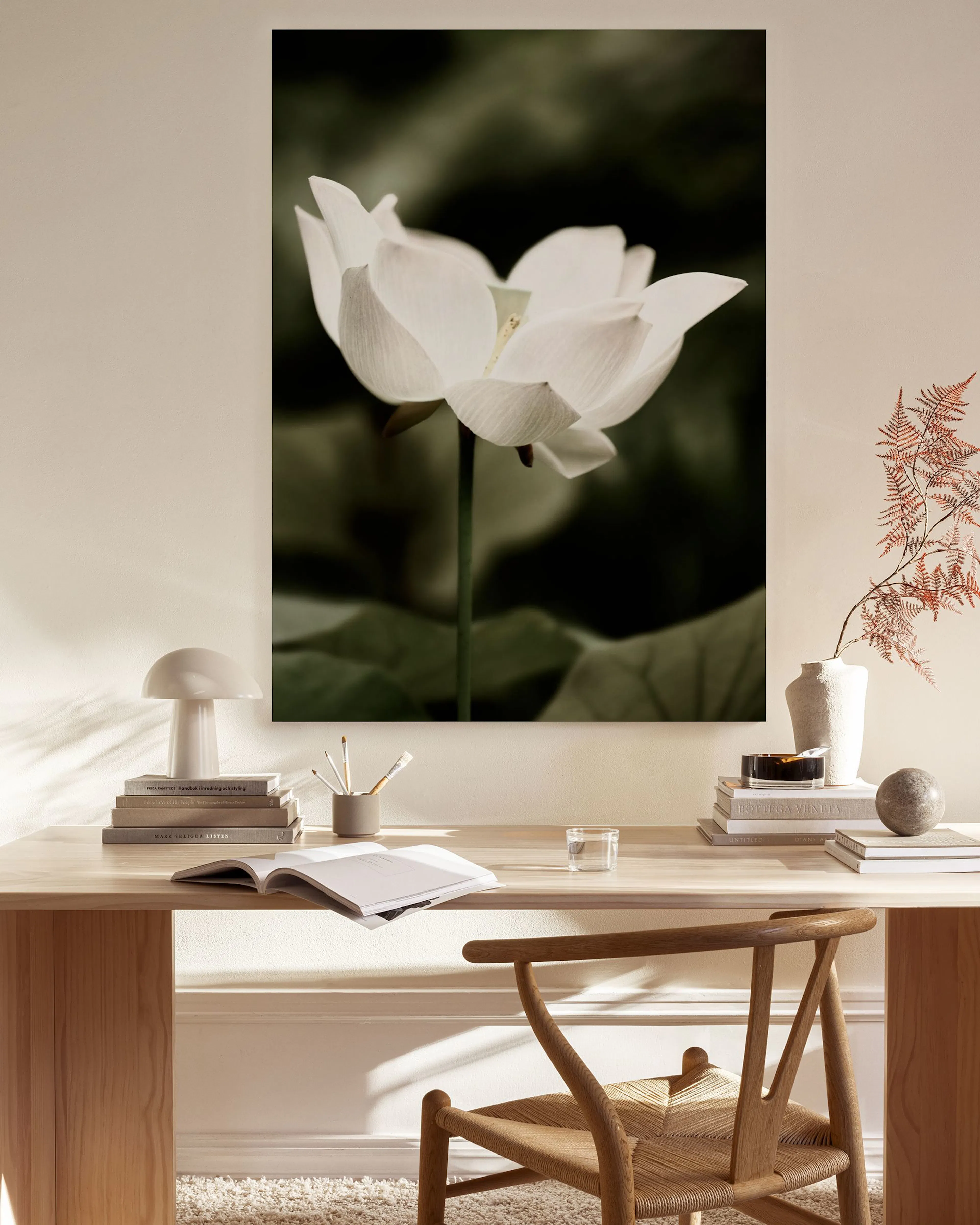 Toile dune fleur de lotus blanche sur fond sombre, suspendue dans un salon clair au-dessus dune table basse.