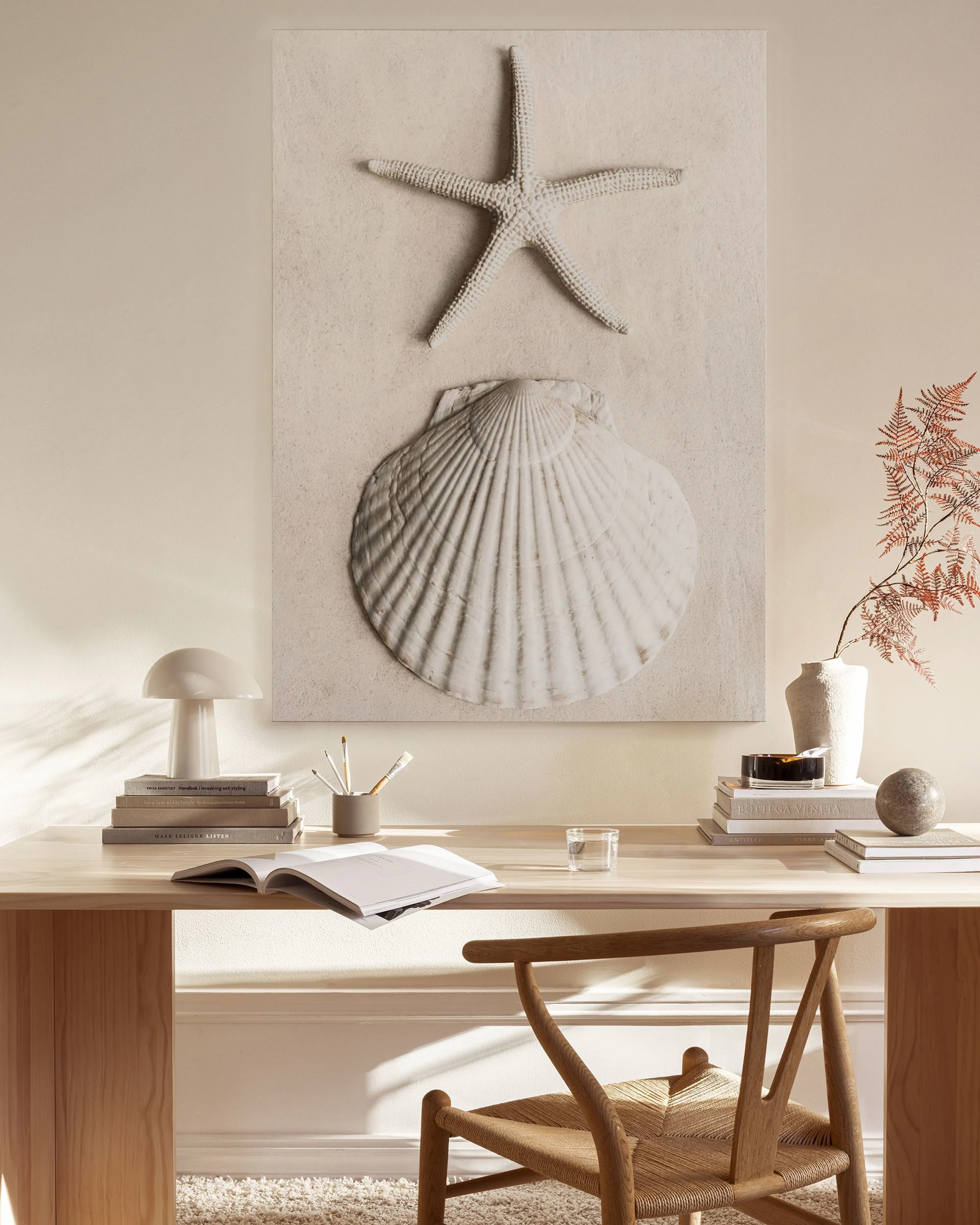 Leinwandbild mit Seestern und Muschel auf Sand in einem modernen Wohnzimmer über einem Sideboard.