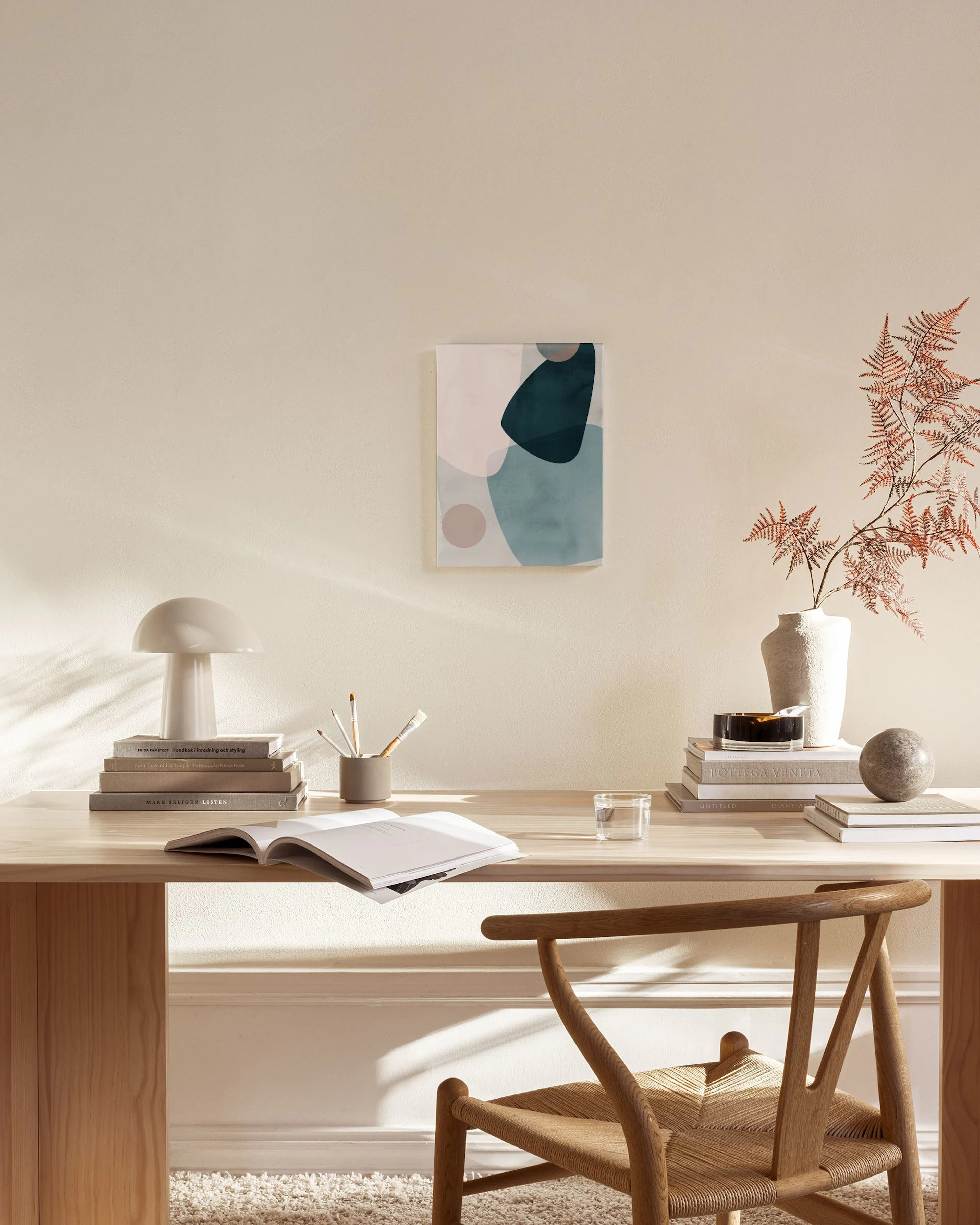 An abstract canvas print with teal, light blue, and pink organic shapes, hanging in a modern living room.