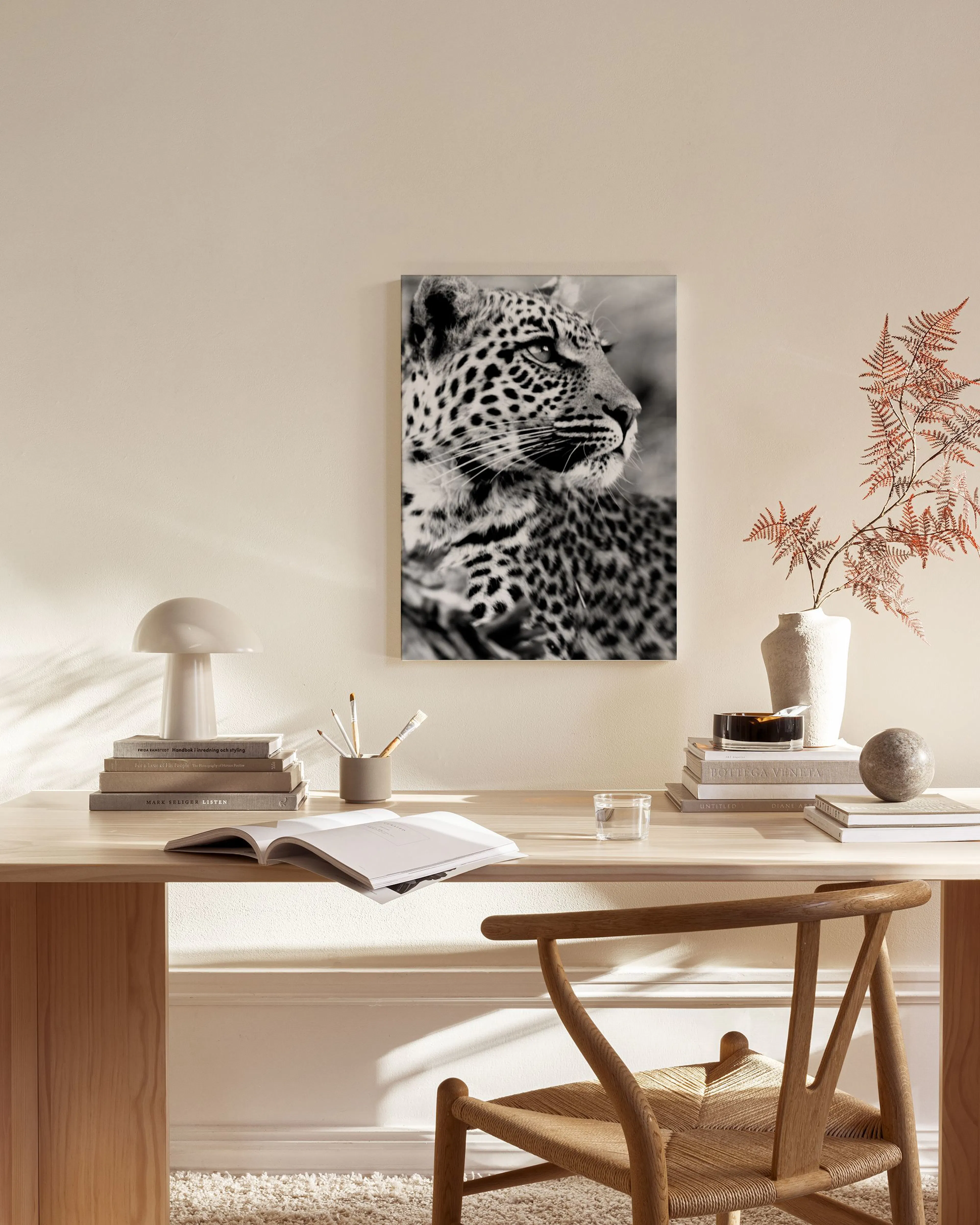 Čiernobiely obraz na plátne s detailnou hlavou leoparda hľadiaceho doprava, visiaci v modernom interiéri nad komodou.
