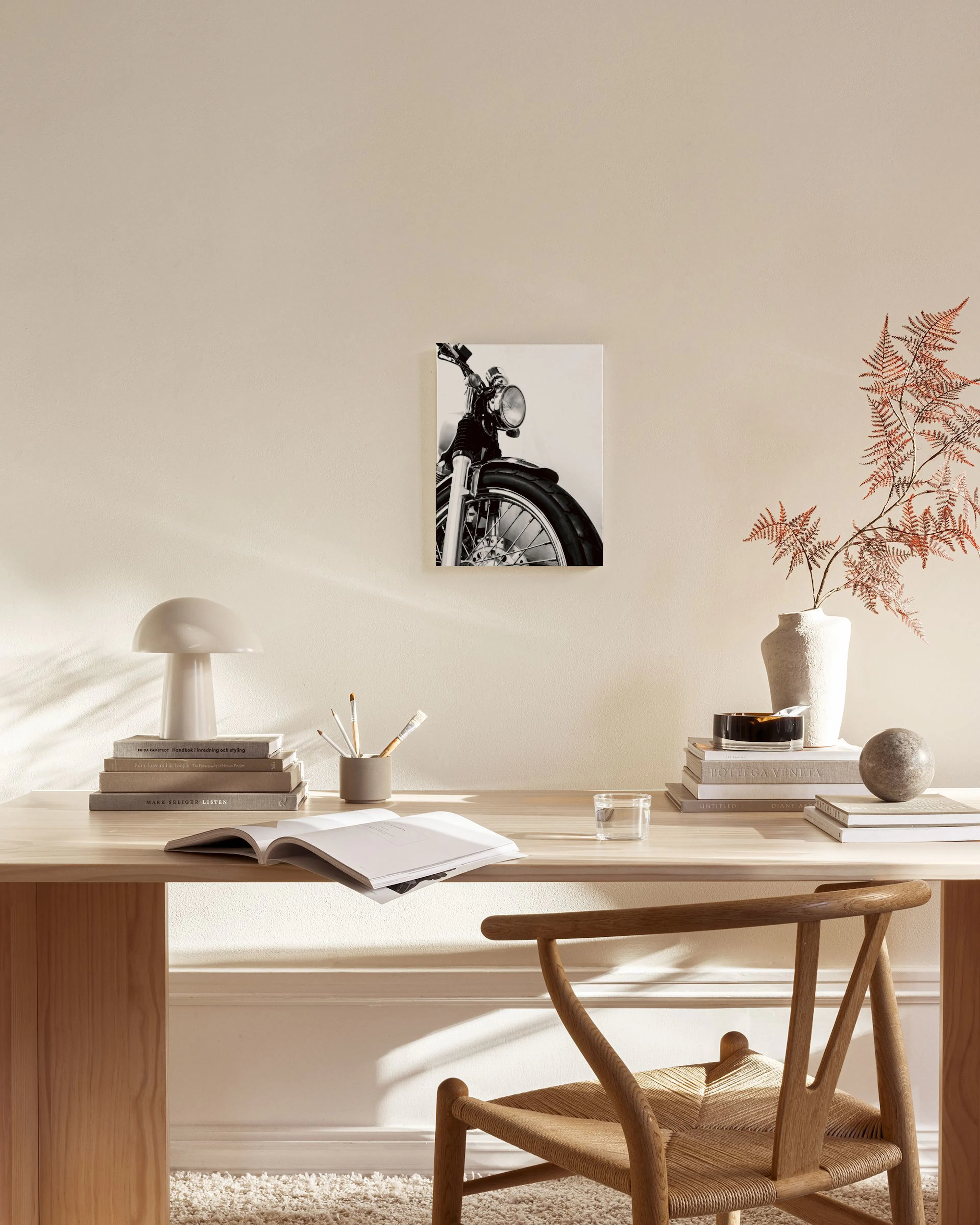 Zwart-wit canvas van een motorfiets, getoond in een moderne woonkamer boven een dressoir.