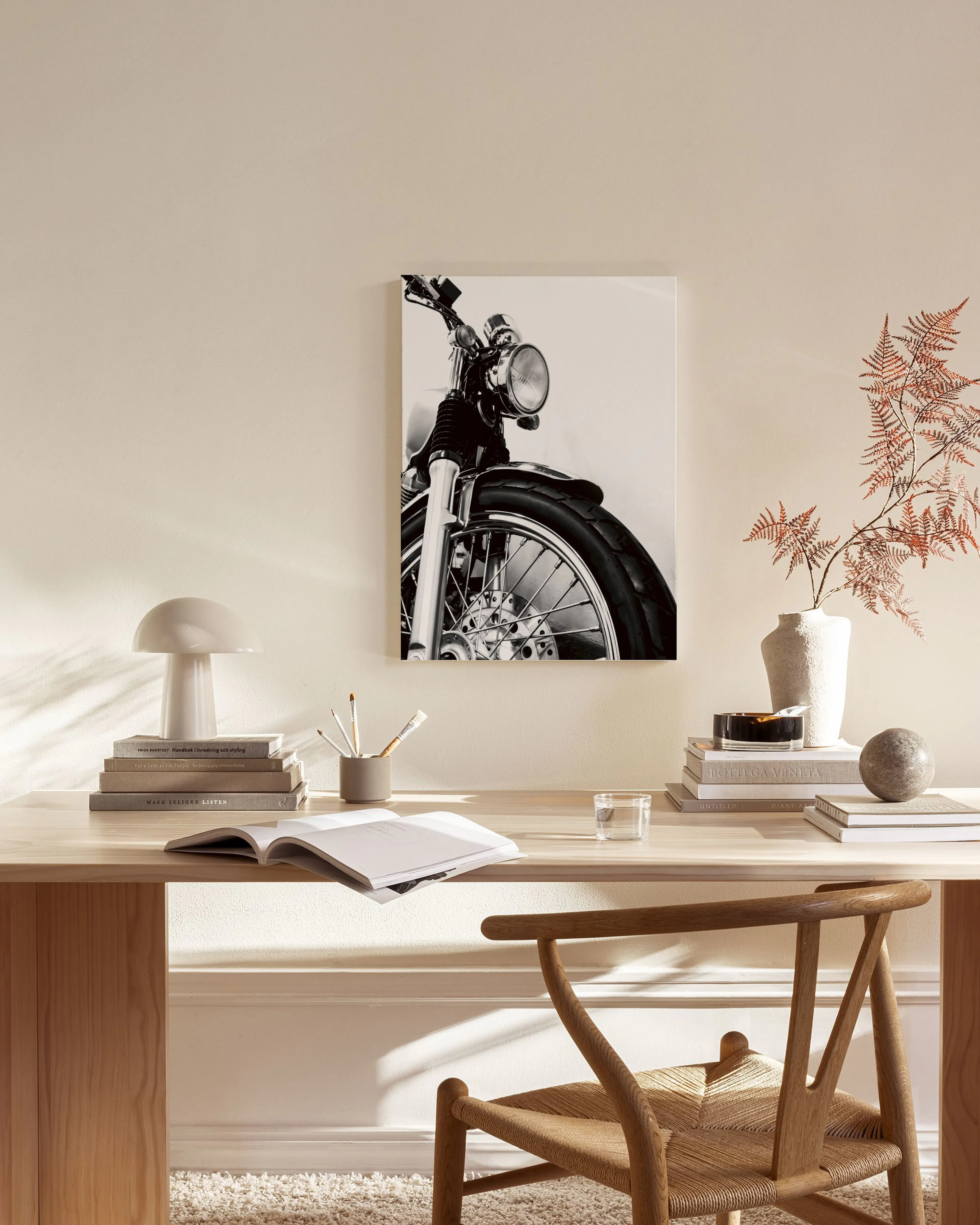 Black and white print of a classic motorcycles front wheel and headlight, hanging in a modern living room.