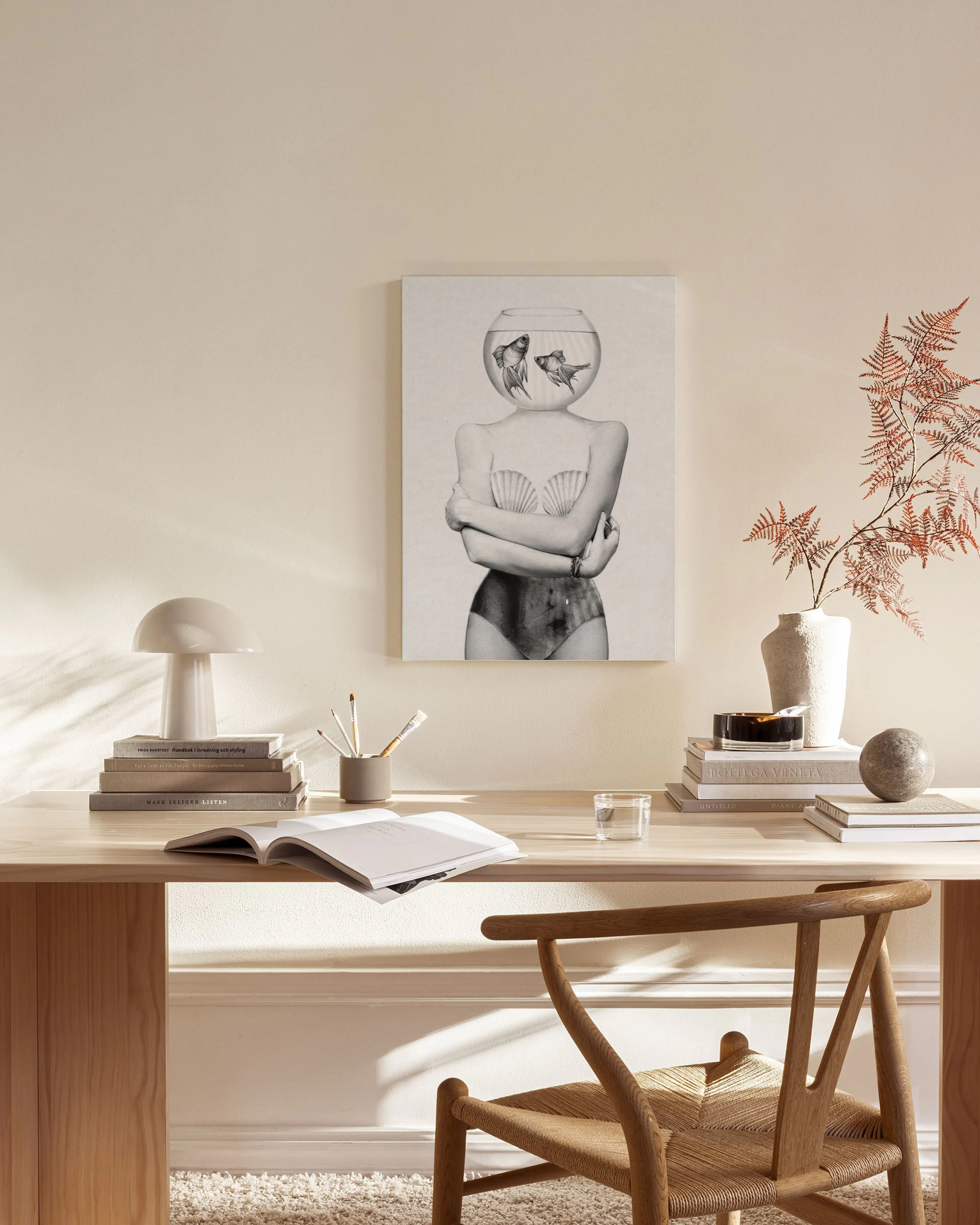 Tela decorativa com mulher em fato de banho e aquário com peixes na cabeça, pendurada numa sala de estar minimalista.