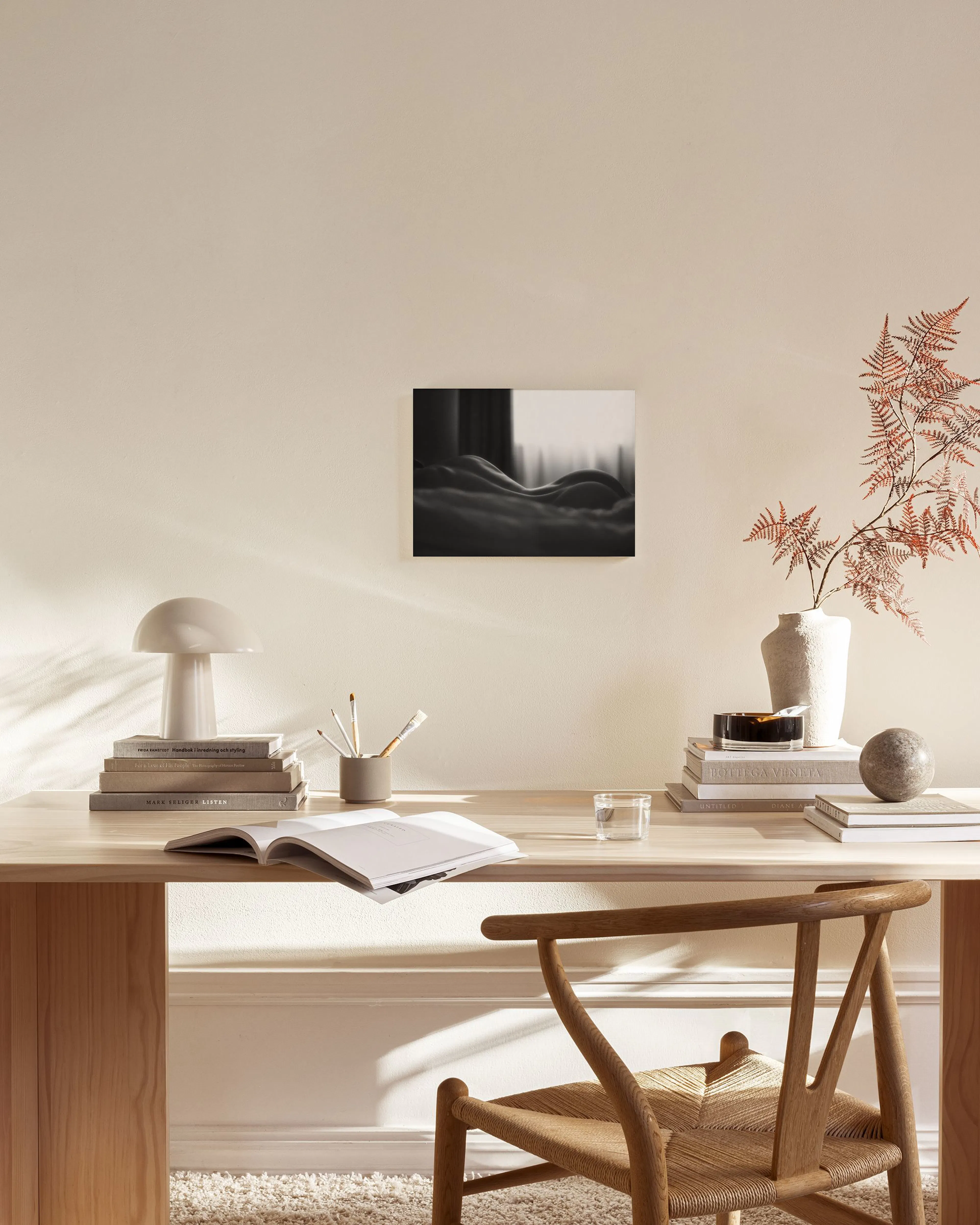 A black and white canvas print of a persons back and hips, hanging in a minimalist living room.